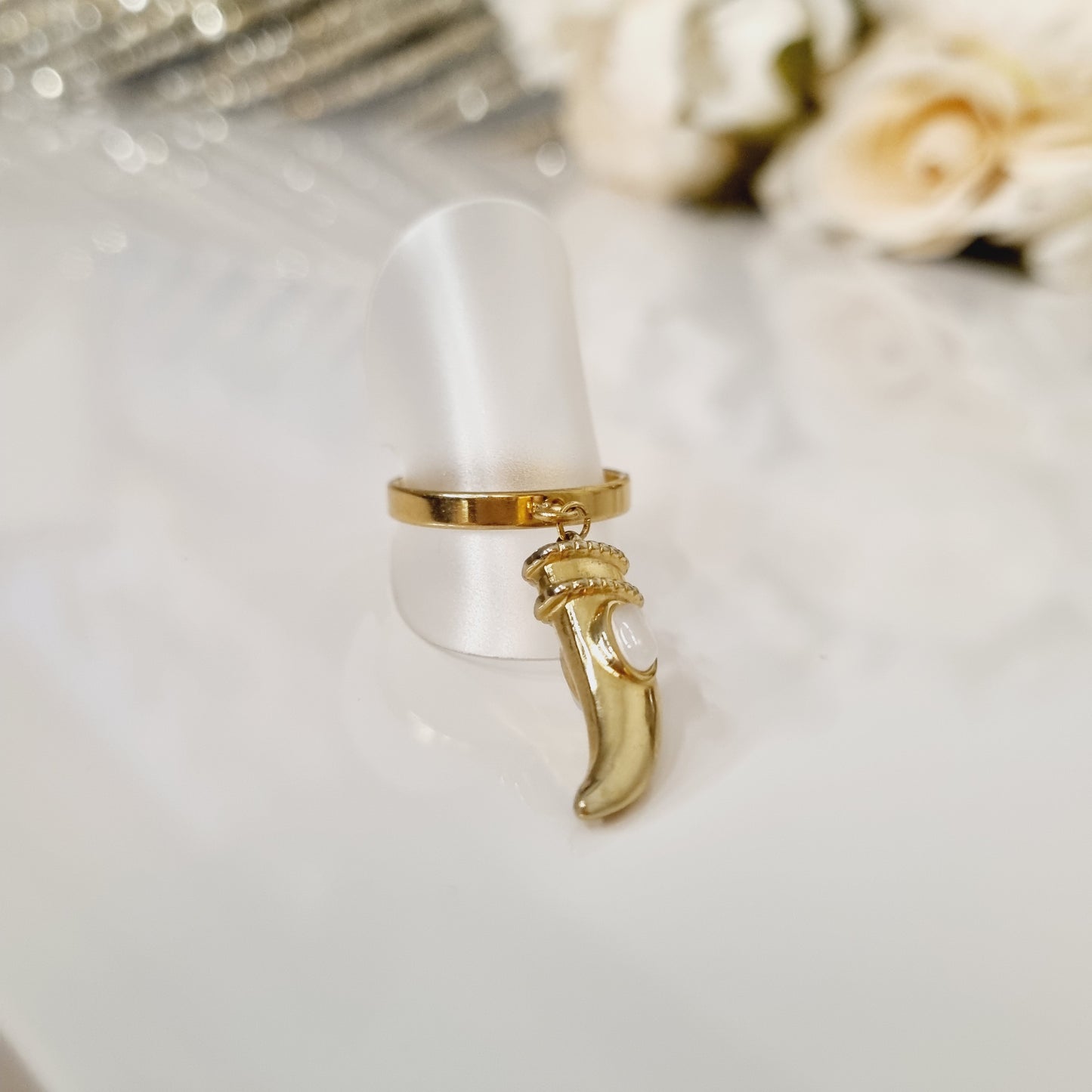 Bague en acier inoxydable couleur or avec breloque en forme de dent de requin, avec pierre blanche. 7mm de diamètre intérieur. L'acier chirurgical / inox / inoxydable (peut être appelé de plusieurs manières différentes) résiste à l'eau et à tout type de liquide. Vous pouvez dormir avec, vous laver/baigner avec, faire du ménage avec sans craindre que la bague ne s'abime. Cette matière garde son éclat au fil des années et est hypoallergénique, elle convient donc pour les personnes sujettes aux allergies.