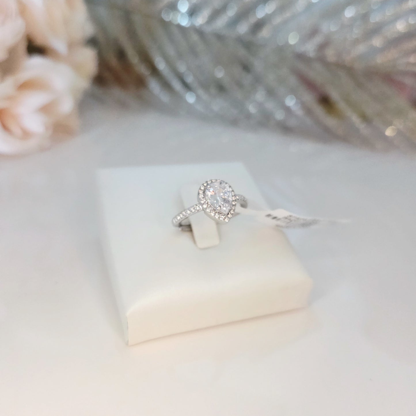 Bague à pierre centrale forme poire portée à la main en lumière naturelle