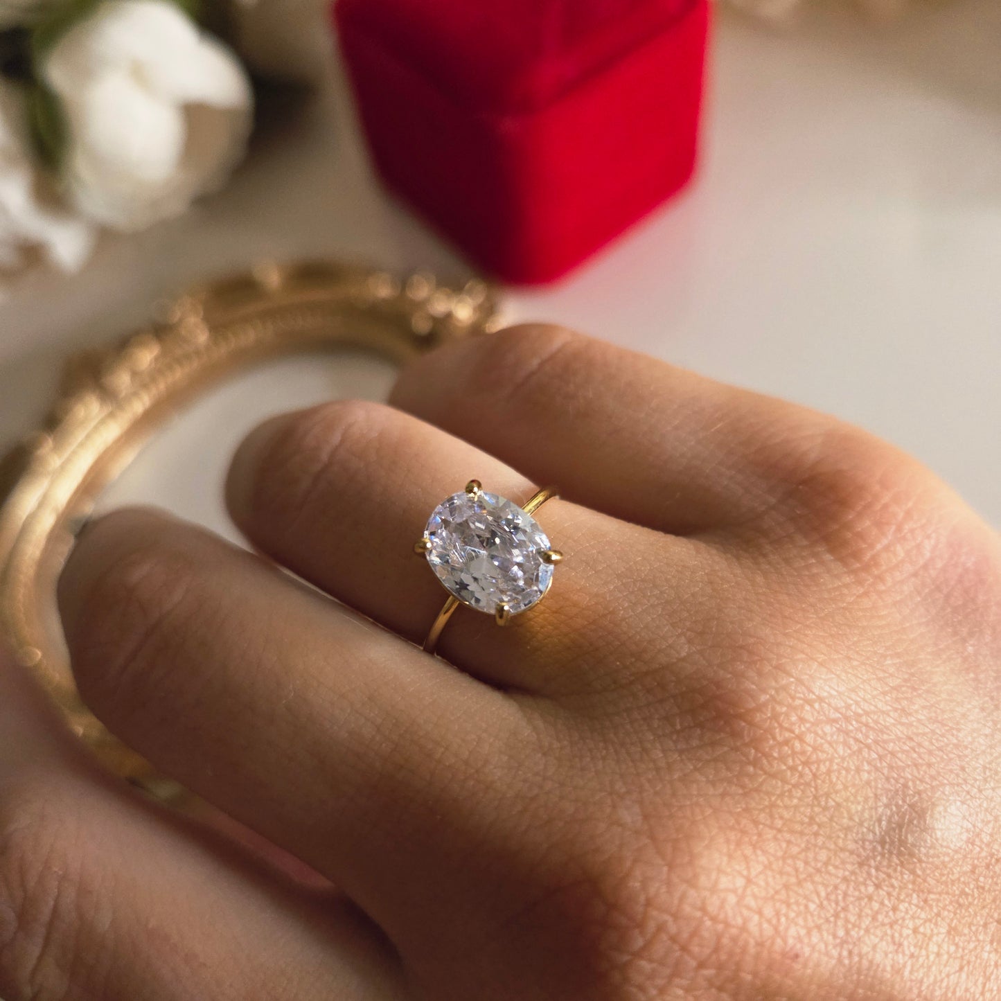 Craquez pour la bague solitaire dorée avec pierre ronde étincelante, livrée dans un écrin rouge. Cadeau idéal pour un anniversaire, une demande ou une surprise romantique. Photo portée.