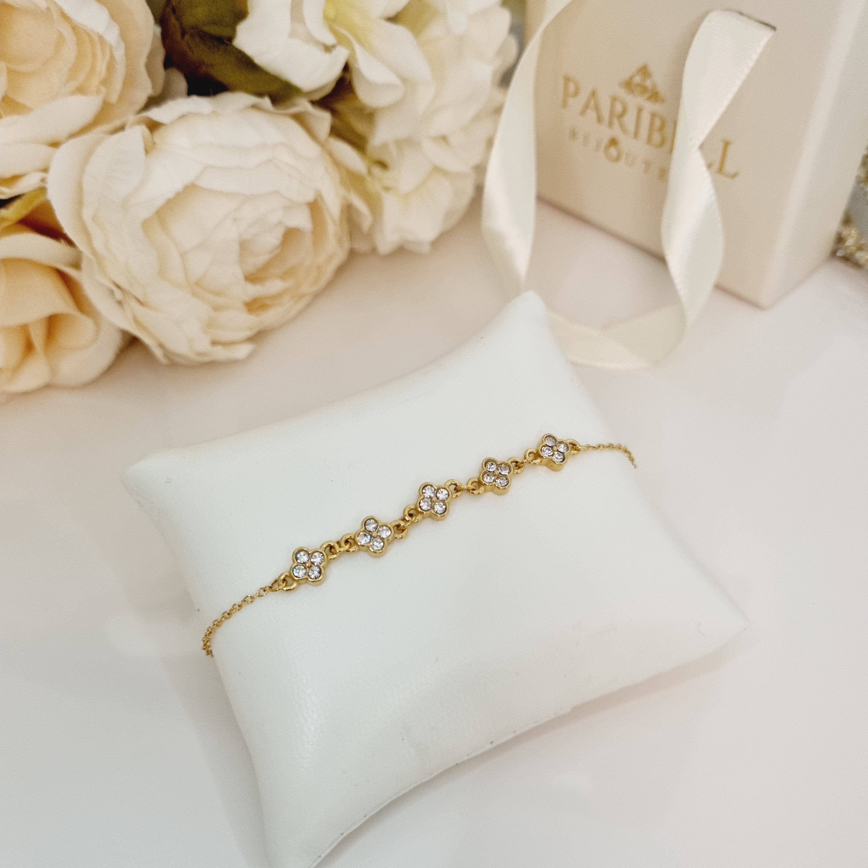 Bracelet doré à chaine réglable en acier inoxydable pour femmes. Avec jolis zircons disposés en forme de fleurs. Parfait comme idée cadeau de qualité.