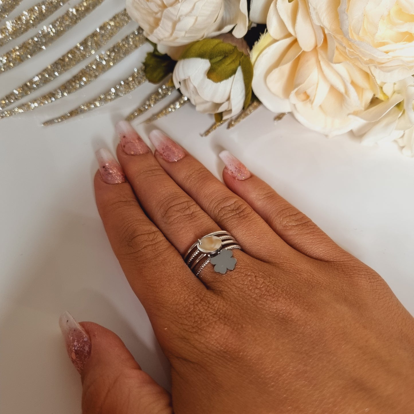 Gros plan sur les breloques médaille et trèfle à 4 feuilles de la bague Alina