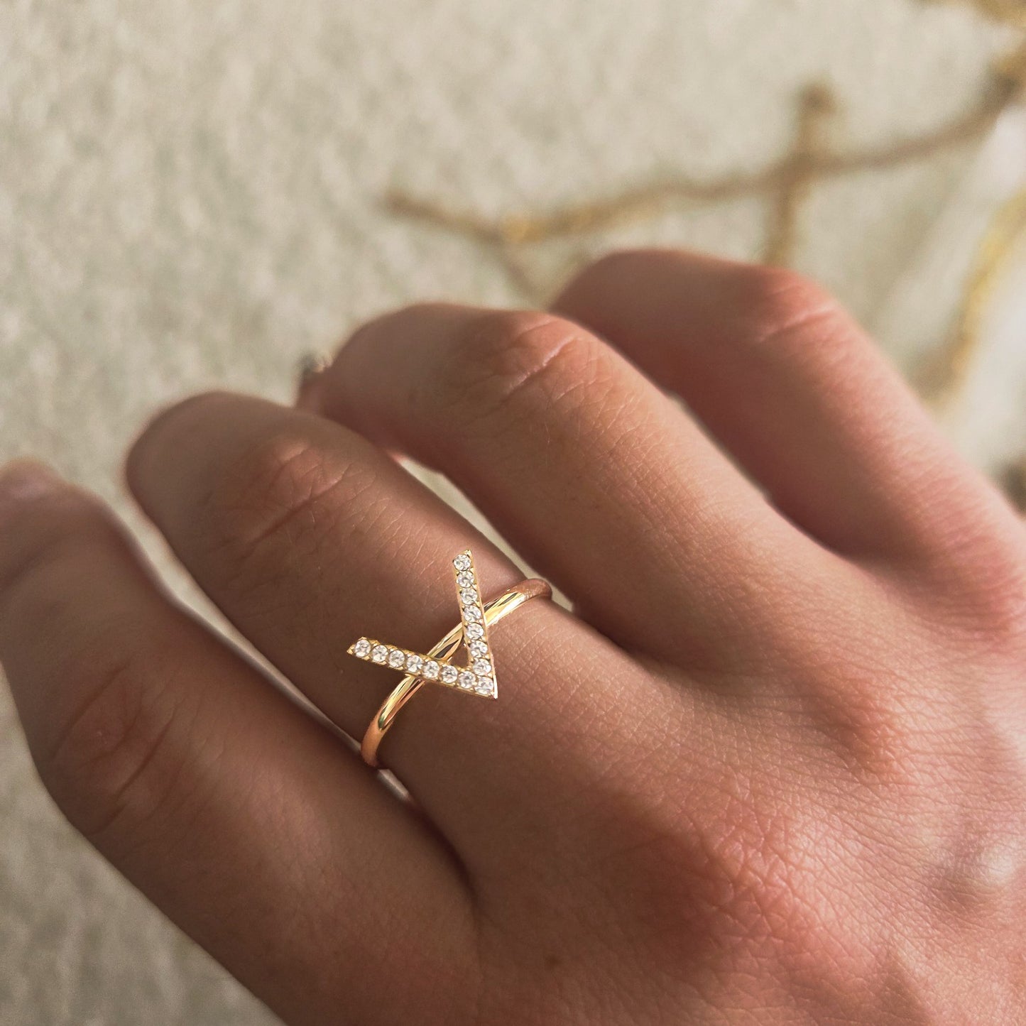 Bague dorée en forme de chevron pavée de strass portée à la main
