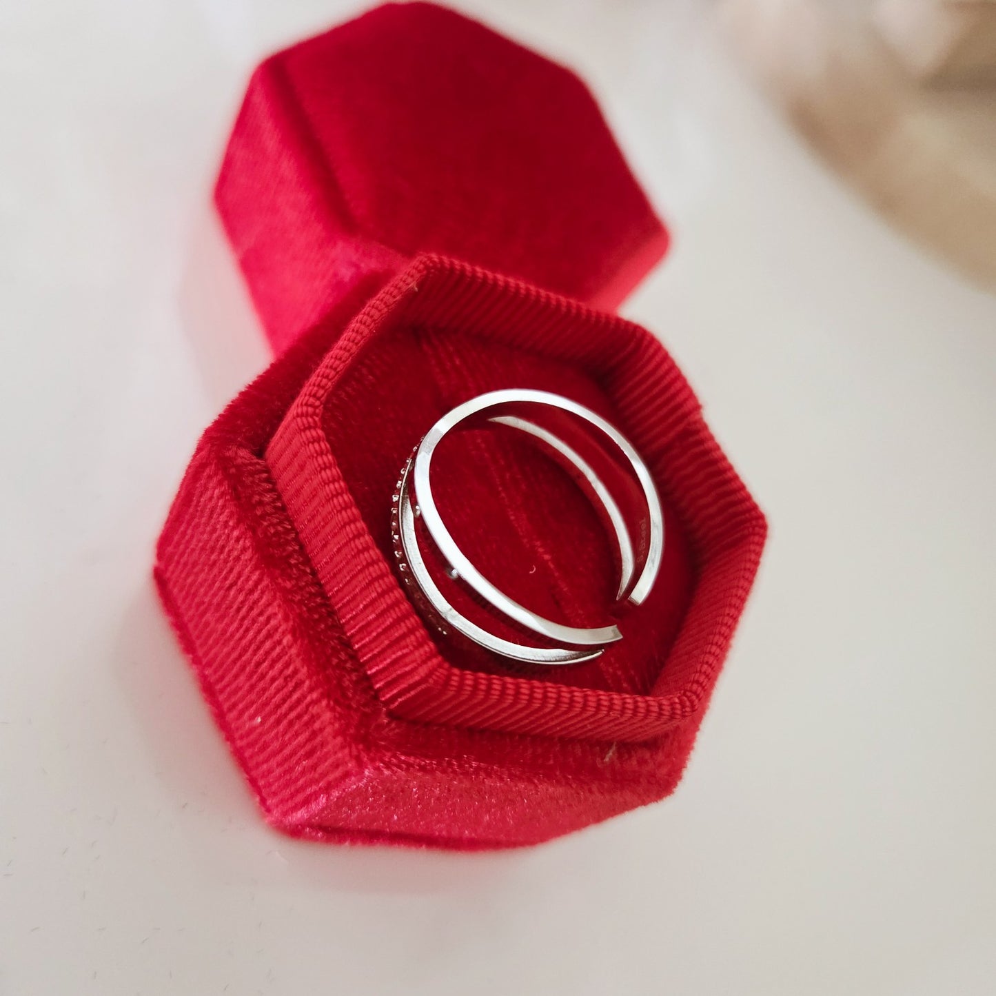 Vue arrière d'une bague croisée argentée réglable dans un écrin rouge