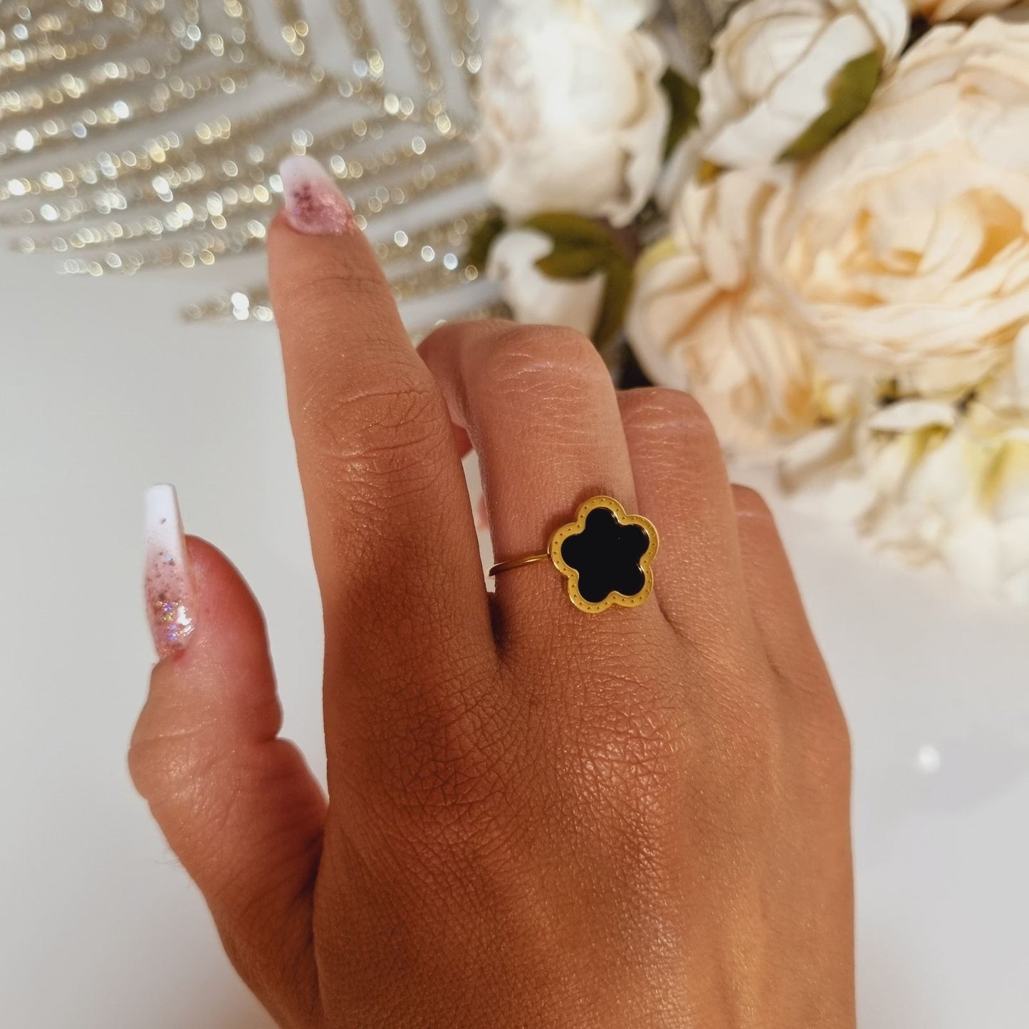 Photo portée d'une bague en acier inoxydable, couleur or, ornée d'une pierre noire représentant un trèfle à 5 feuilles. Symbole de porte-bonheur. Parfaite pour offrir, taille réglable, convient à toutes les tailles.