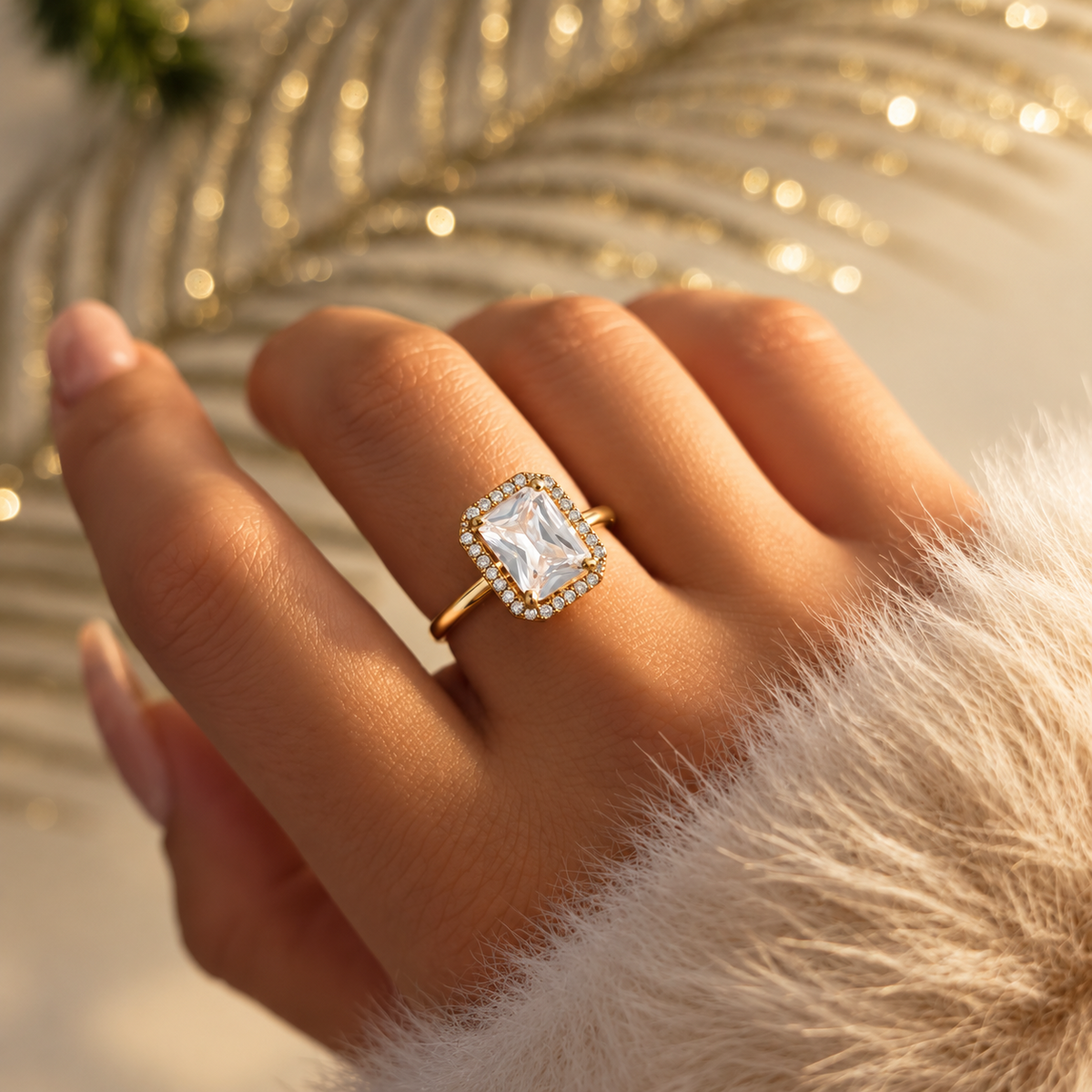 Bague dorée à grande pierre rectangulaire transparente entourée de petites pierres, portée à la main