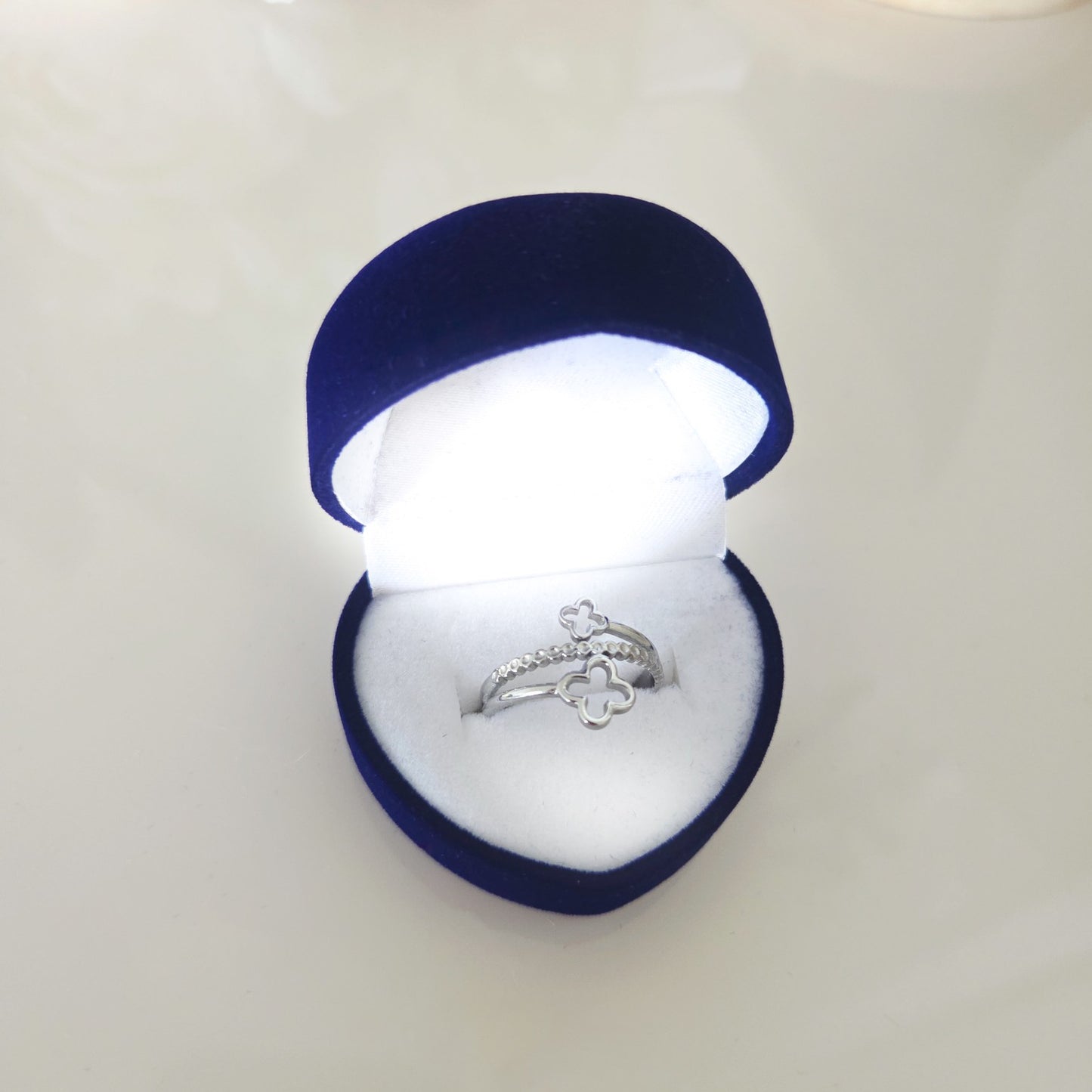 Bague réglable double trèfle argentée présentée dans un écrin bleu