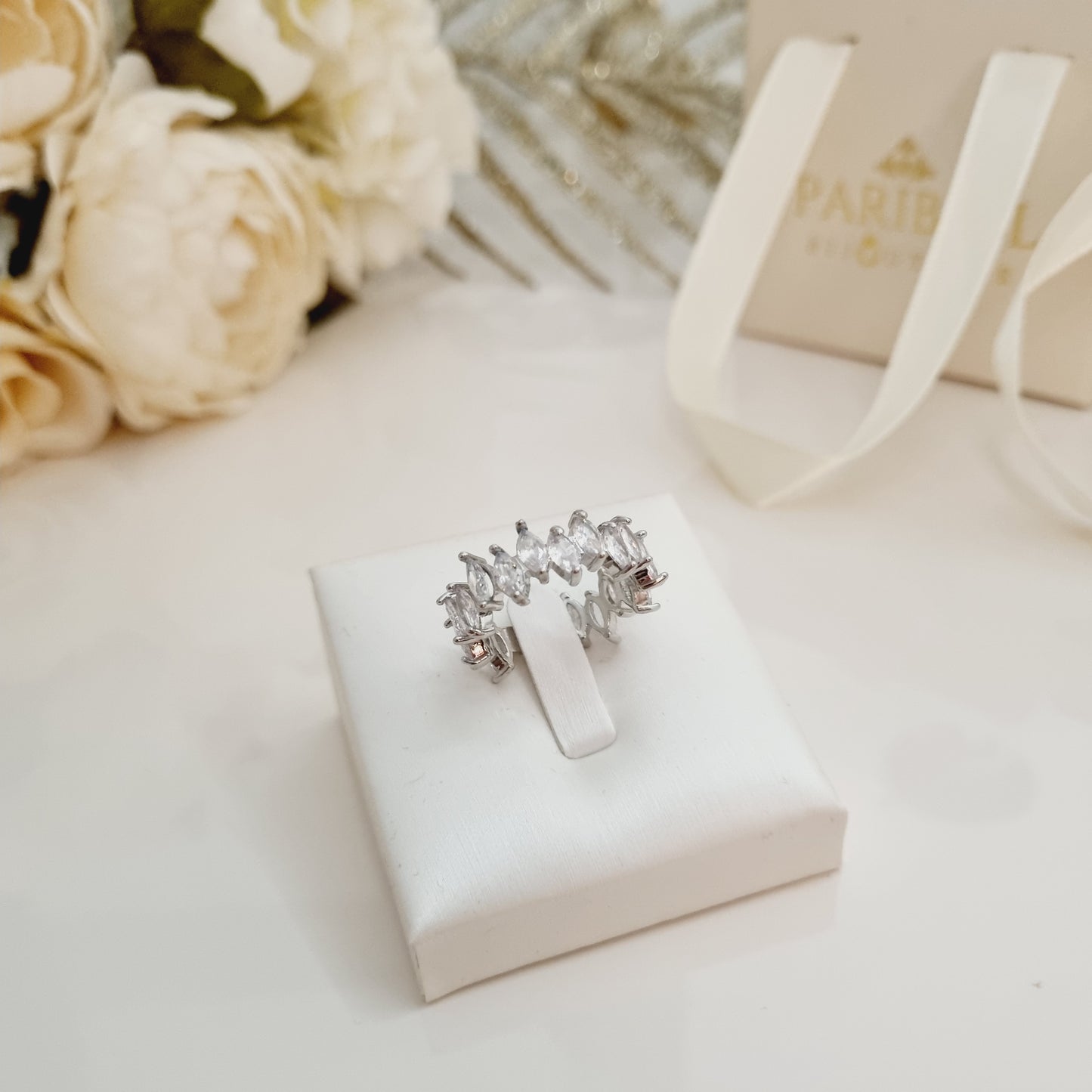 Bague Alina en acier inoxydable doré avec pierres brillantes sur support blanc – Bijou ajustable élégant. Idée cadeau fête des mères