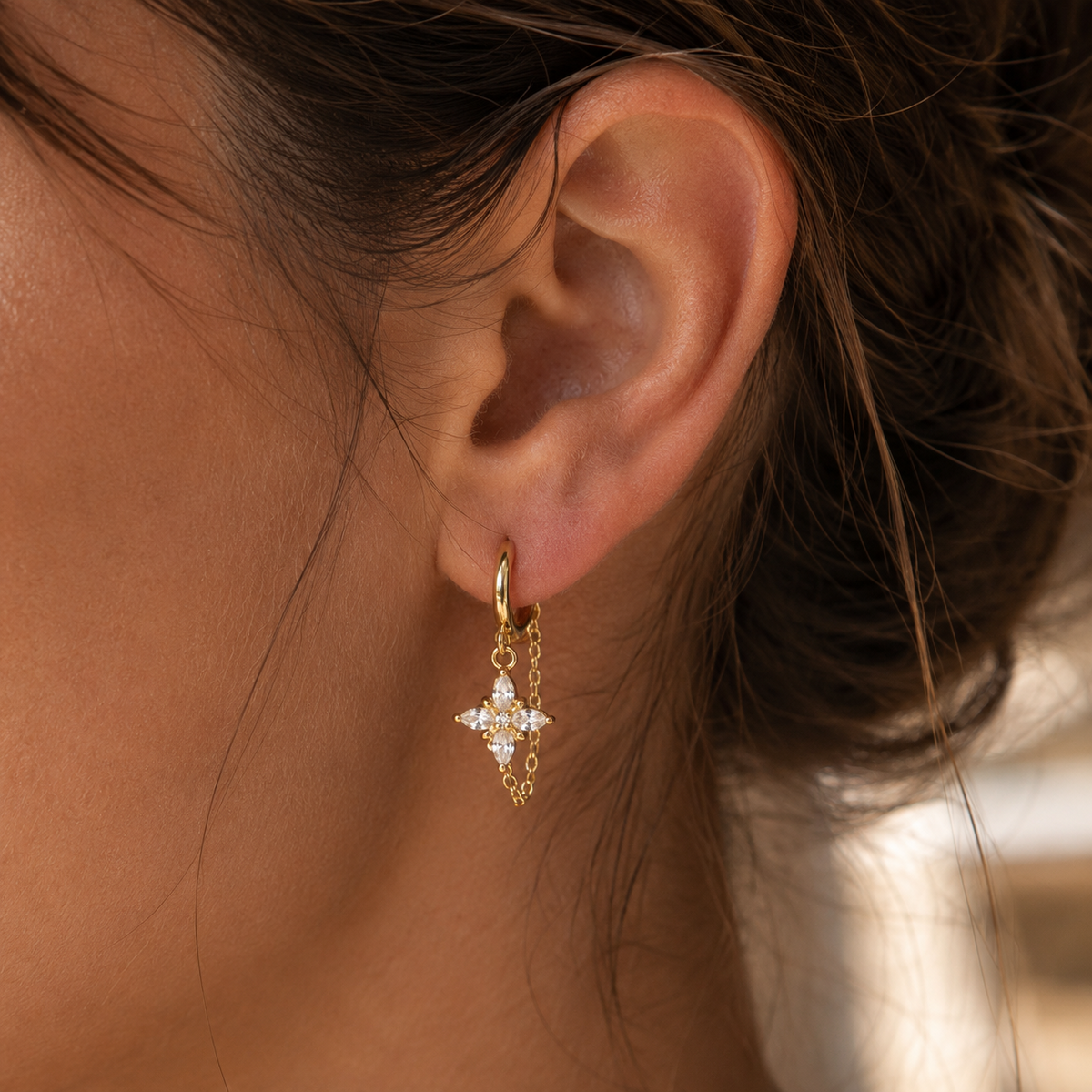 Boucles d’oreilles dorées avec pendentif fleur, chaîne fine et pierres blanches