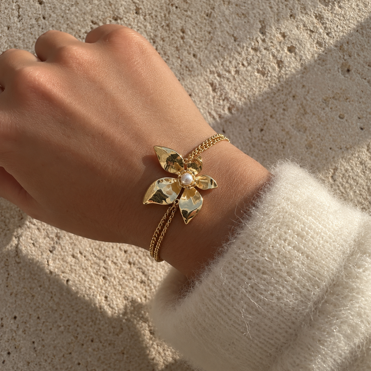 Bracelet doré à chaînes fines et fleur aux pétales texturés avec perle blanche centrale
