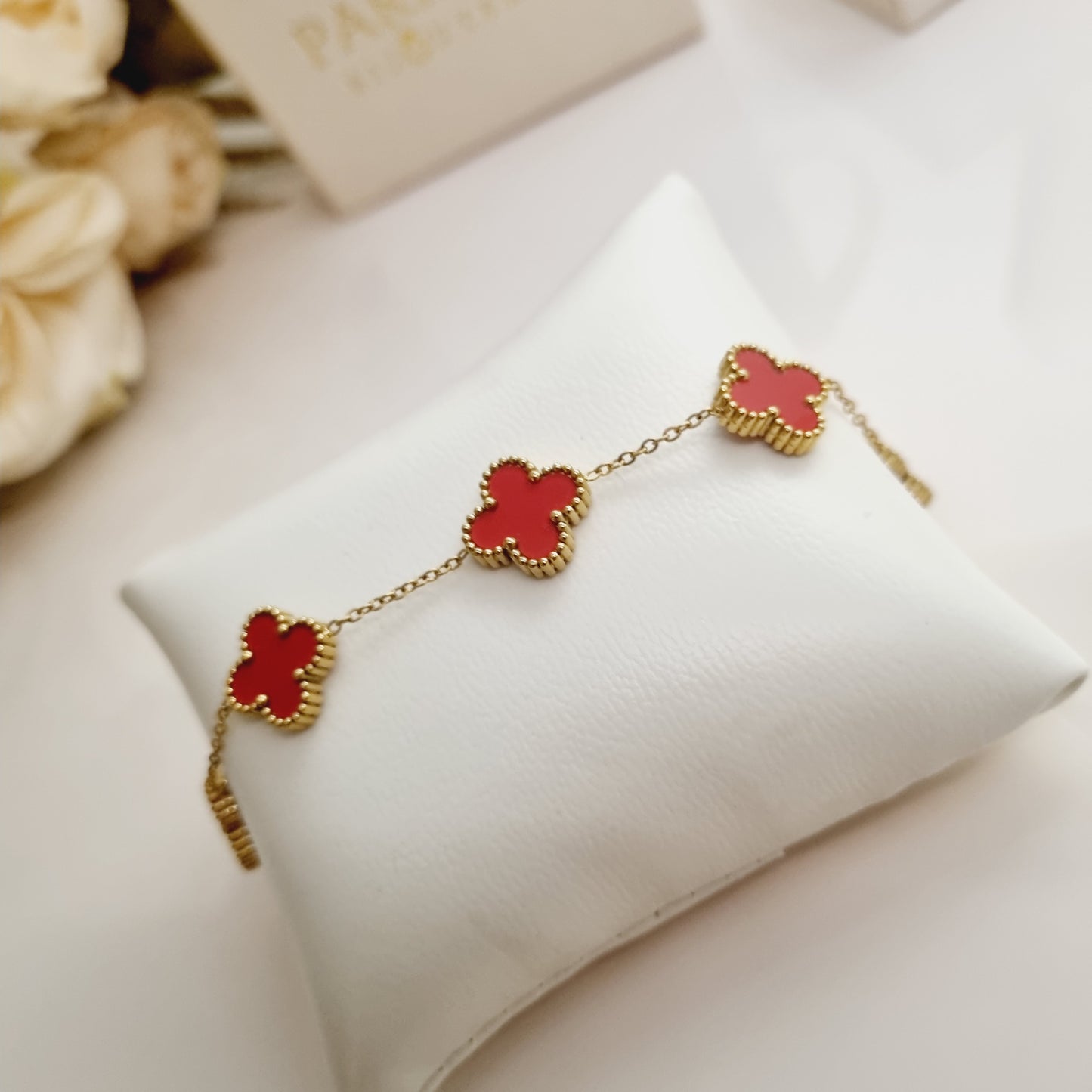 Bracelet doré Liora avec trèfles à quatre feuilles et pierre rouge vue de face