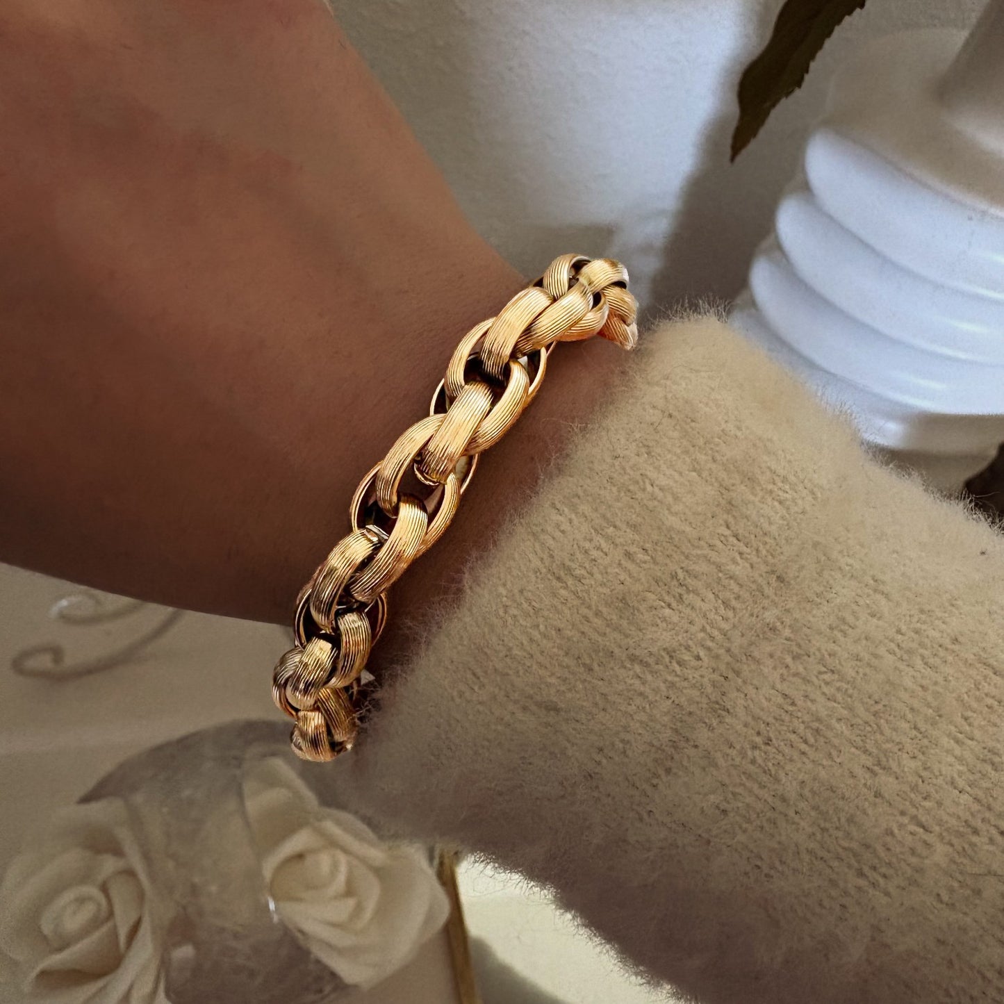 Bracelet large à maille tressée dorée porté au poignet