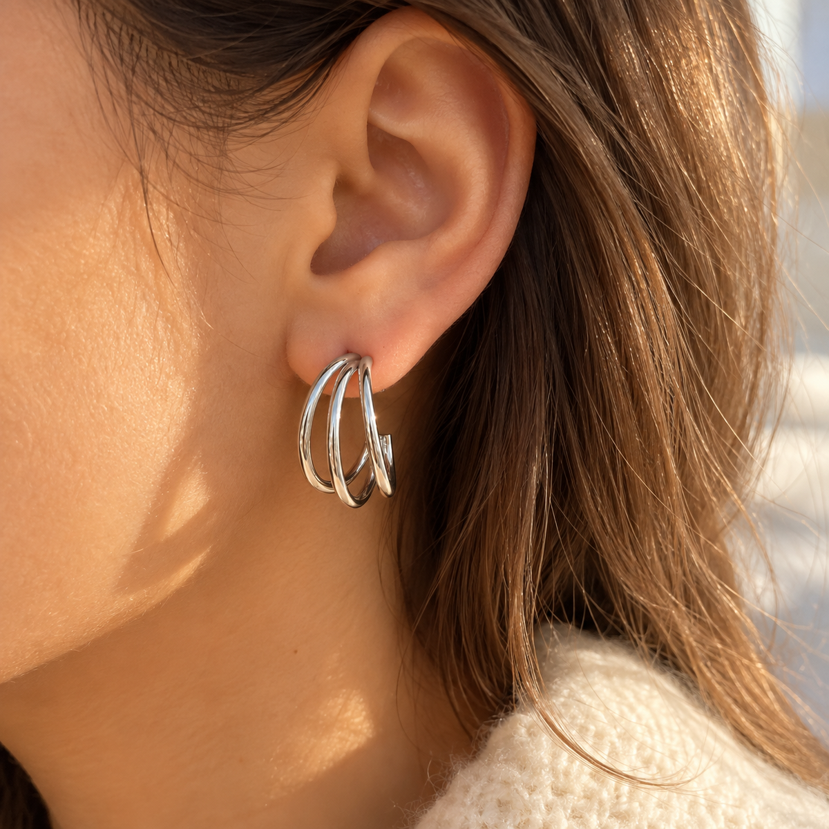 Boucle d’oreille créole argentée à trois anneaux lisses superposés, portée à l’oreille