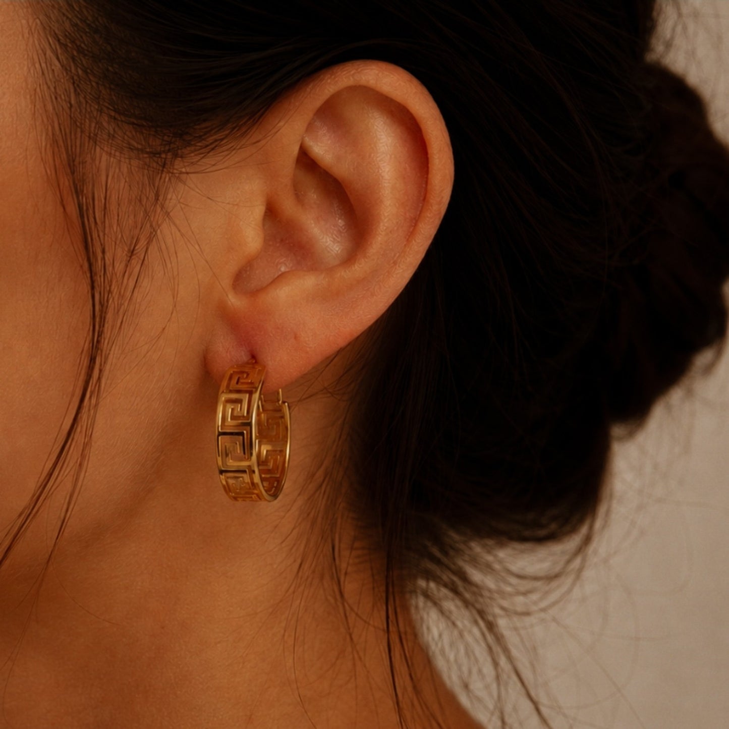 Créole dorée à motif géométrique, 3,2 cm de diamètre et 1 cm de largeur, portée à l’oreille