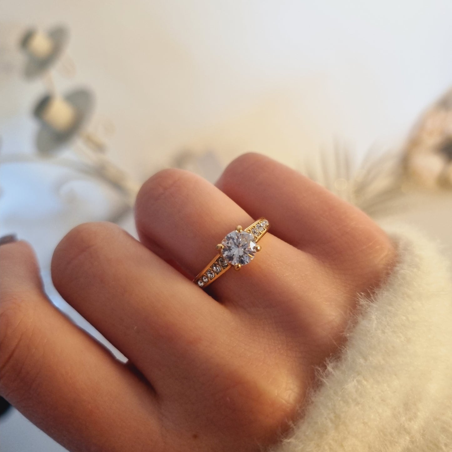 Photo portée de la bague Aliona, bague dorée en acier inoxydable avec pierres latérales et zirconium central. Idéale comme idée cadeau roantique.