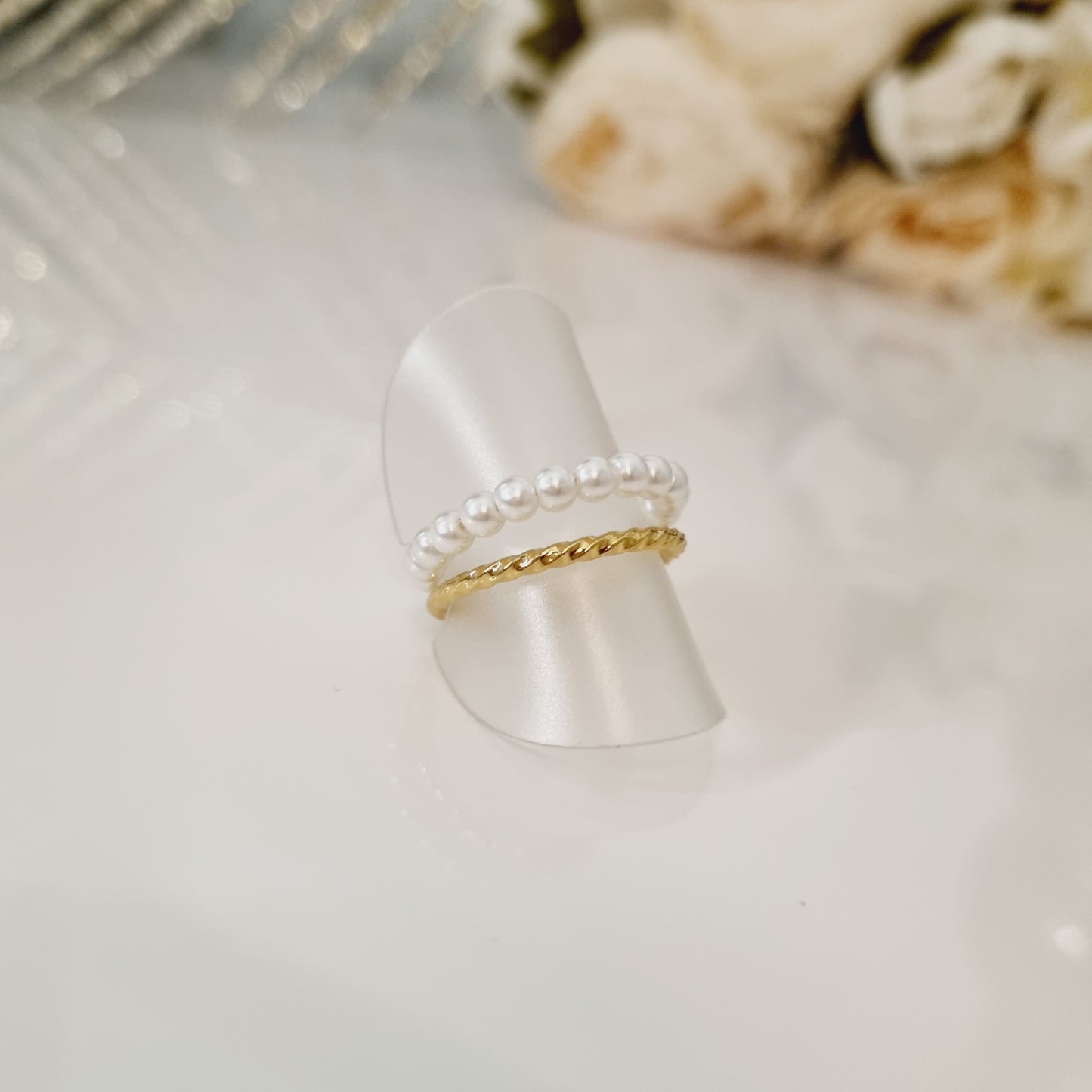 Bague en acier inoxydable couleur or, avec perles blanches. Taille réglable, cntient pour toutes les tailles des doigts. L'acier chirurgical / inox / inoxydable (peut être appelé de plusieurs manières différentes) résiste à l'eau et à tout type de liquide. Vous pouvez dormir avec, vous laver/baigner avec, faire du ménage avec sans craindre que la bague ne s'abime. Cette matière garde son éclat au fil des années et est hypoallergénique, elle convient donc pour les personnes sujettes aux allergies.