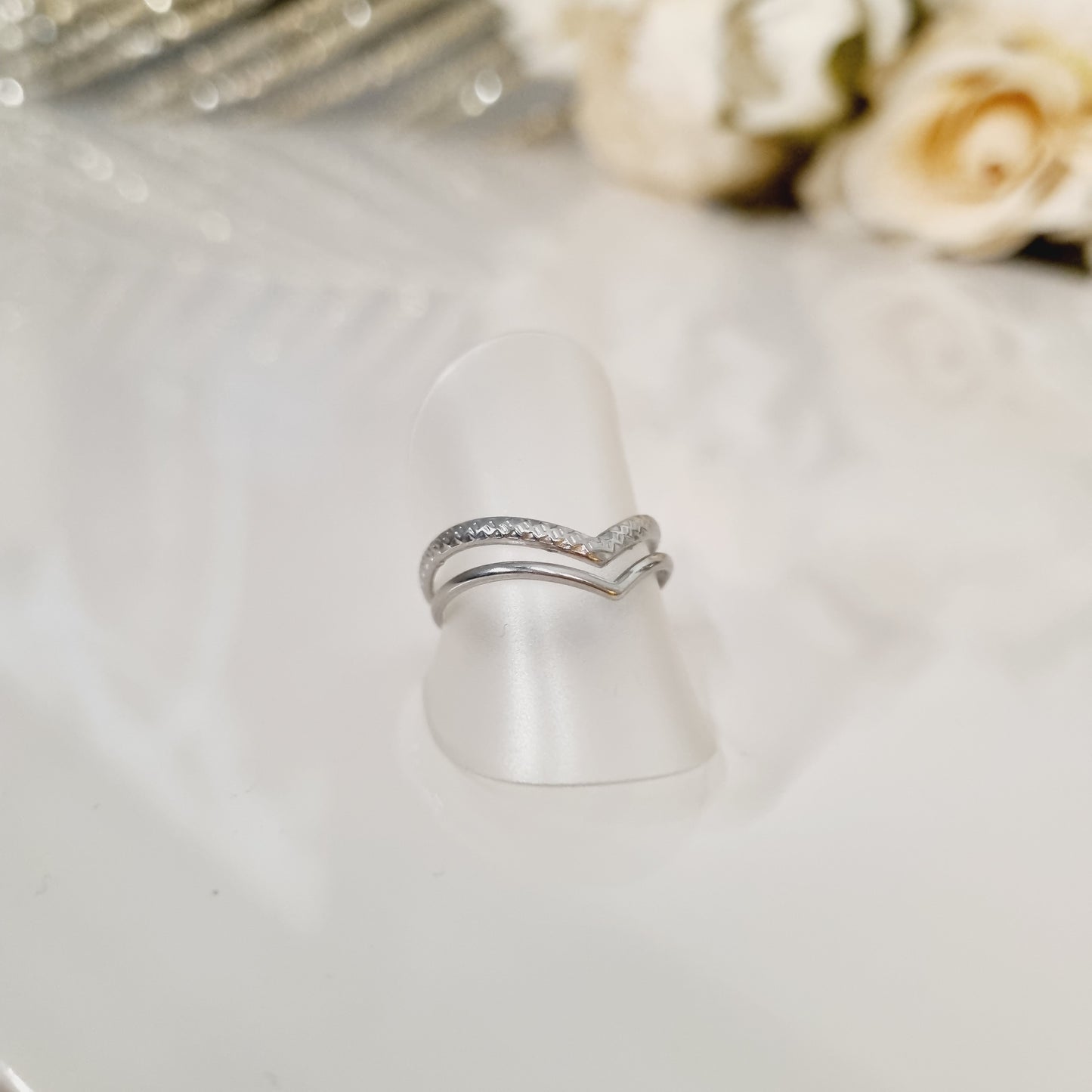 Bague en acier inoxydable couleur argent en forme de v double. Taille réglable, cntient pour toutes les tailles des doigts. L'acier chirurgical / inox / inoxydable (peut être appelé de plusieurs manières différentes) résiste à l'eau et à tout type de liquide. Vous pouvez dormir avec, vous laver/baigner avec, faire du ménage avec sans craindre que la bague ne s'abime. Cette matière garde son éclat au fil des années et est hypoallergénique, elle convient donc pour les personnes sujettes aux allergies.