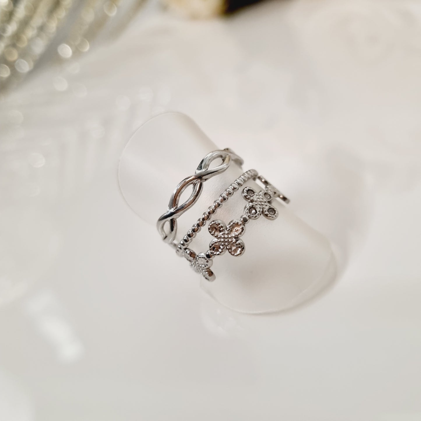 Bague en acier inoxydable couleur argent multirang avec trèfle et maille. Taille réglable, convient à toutes les tailles. L'acier chirurgical / inox / inoxydable (peut être appelé de plusieurs manières différentes) résiste à l'eau et à tout type de liquide. Vous pouvez dormir avec, vous laver/baigner avec, faire du ménage avec sans craindre que la bague ne s'abime. Cette matière garde son éclat au fil des années et est hypoallergénique, elle convient donc pour les personnes sujettes aux allergies.