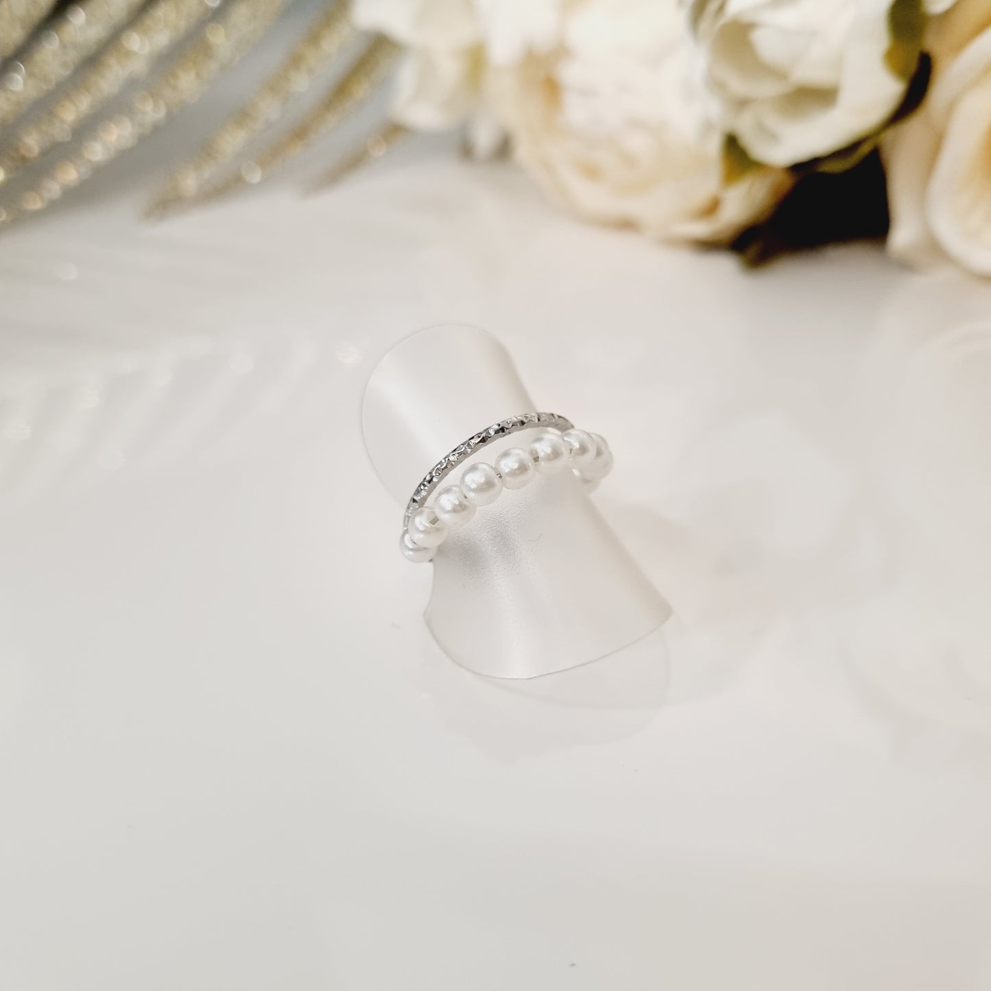 Bague en acier inoxydable couleur argent avec perles blanches. Taille réglable, convient à toutes les tailles. L'acier chirurgical / inox / inoxydable (peut être appelé de plusieurs manières différentes) résiste à l'eau et à tout type de liquide. Vous pouvez dormir avec, vous laver/baigner avec, faire du ménage avec sans craindre que la bague ne s'abime. Cette matière garde son éclat au fil des années et est hypoallergénique, elle convient donc pour les personnes sujettes aux allergies.