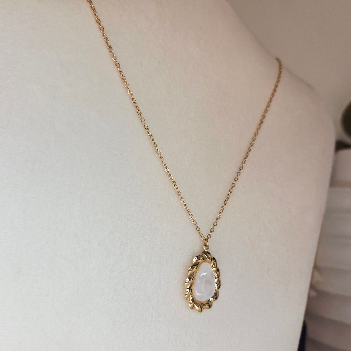 Collier doré et pierre blanche