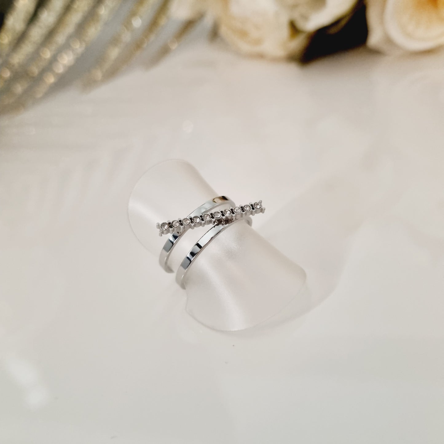 Bague en acier inoxydable couleur argent avec zircons. Taille réglable, convient à toutes les tailles. L'acier chirurgical / inox / inoxydable (peut être appelé de plusieurs manières différentes) résiste à l'eau et à tout type de liquide. Vous pouvez dormir avec, vous laver/baigner avec, faire du ménage avec sans craindre que la bague ne s'abime. Cette matière garde son éclat au fil des années et est hypoallergénique, elle convient donc pour les personnes sujettes aux allergies.