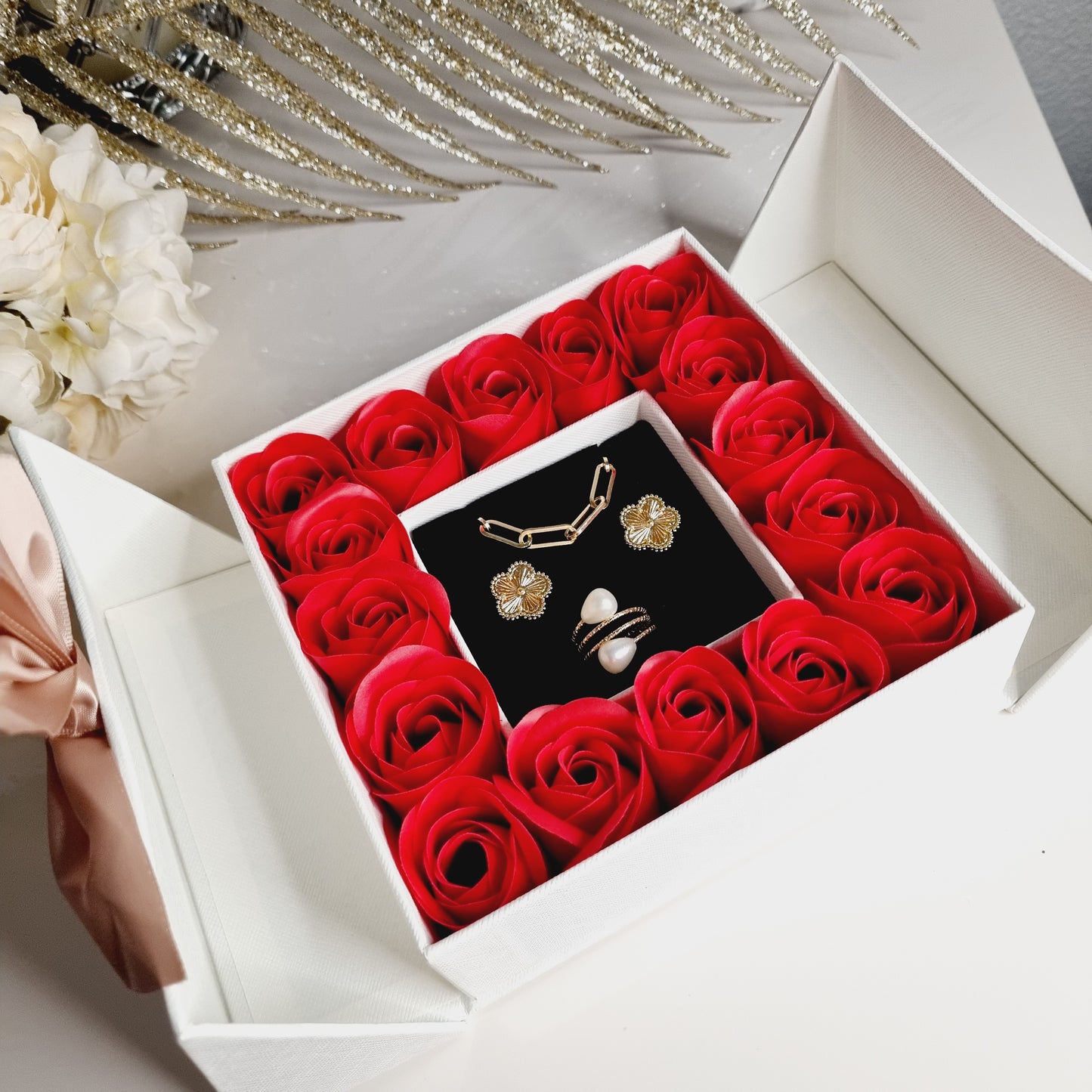 Magnifique coffret cadeau blanc comprenant des roses rouges décoré d'un noeud rose aimanté, qui fera sensation, à offrir ou à se faire plaisir ! Attention, les bijoux sur la photo sont présentés à titre d'exemple. Le coffret est vendu vide. Il faut faire votre propre sélection en ajoutant au panier les bijoux qui vous paisent. Ce coffret peut contenir 3 bijoux : - Collier ou bracelet - Boucles d'oreilles - Bague