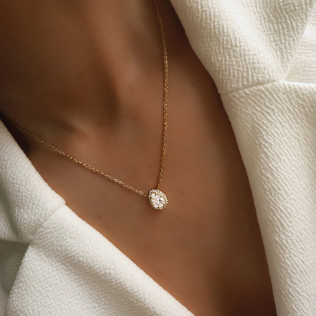 Collier pendentif goutte sertie porté au cou sur une chaîne fine