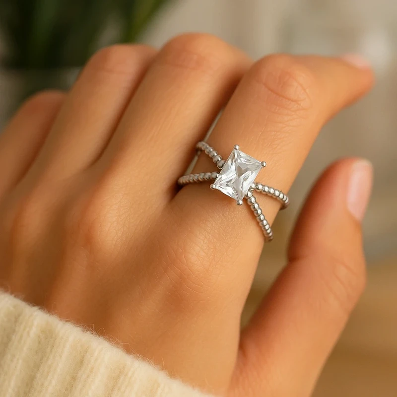 Bague de fiançailles argentée en acier inoxydable, anneau croisé serti d’un zircon rectangulaire éclatant. Élégante et intemporelle.