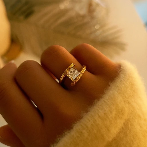 Bague dorée en acier inoxydable ajustable, sertie d’un zircon rectangulaire brillant. Élégante et moderne, parfaite pour un style sophistiqué.