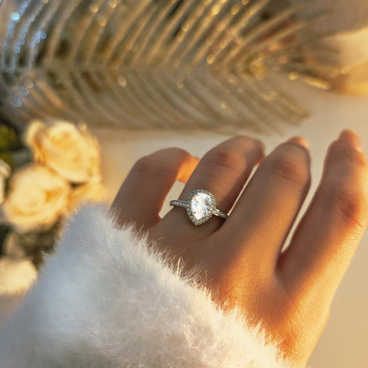 Bague élégante à pierre centrale forme poire portée à la main, bijou raffiné et lumineux
