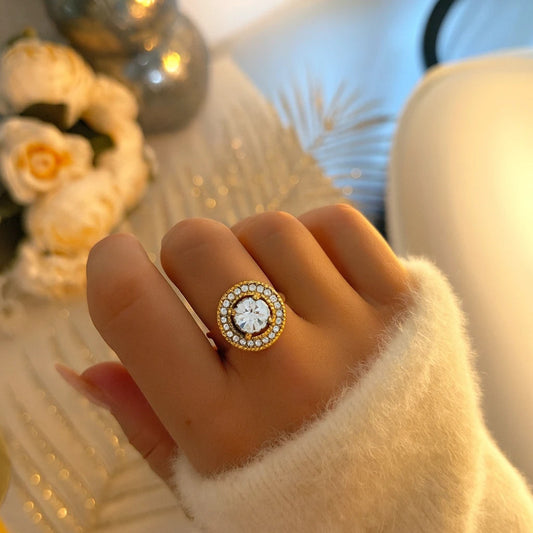Bague femme en acier inoxydable doré avec grand zircon rond central et contour de strass. Bague ajustable disponible en doré ou argenté, élégante et éclatante pour toutes les occasions.