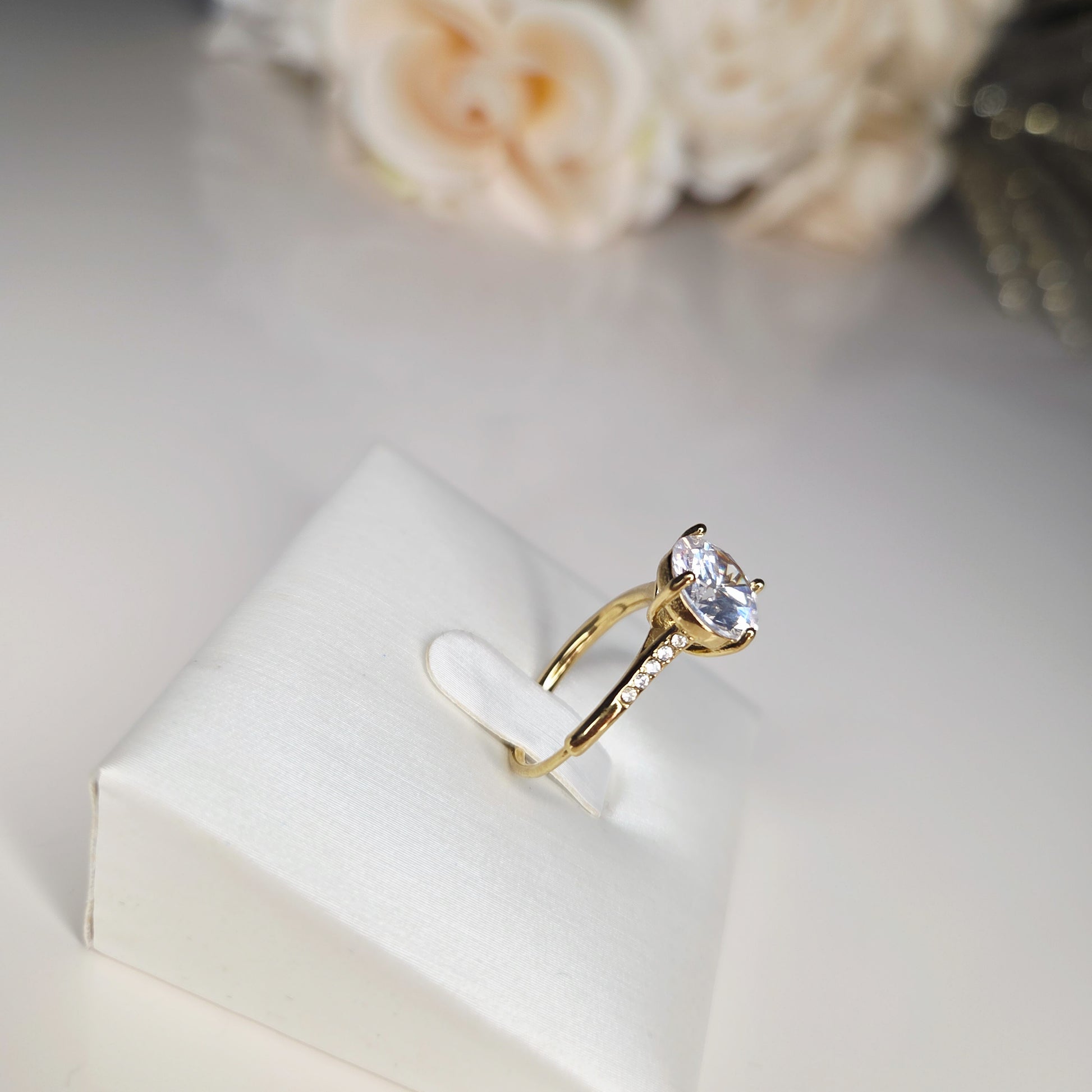 Sublimez vos mains avec cette bague solitaire dorée, mise en valeur par une pierre ronde étincelante. Vue de côté.