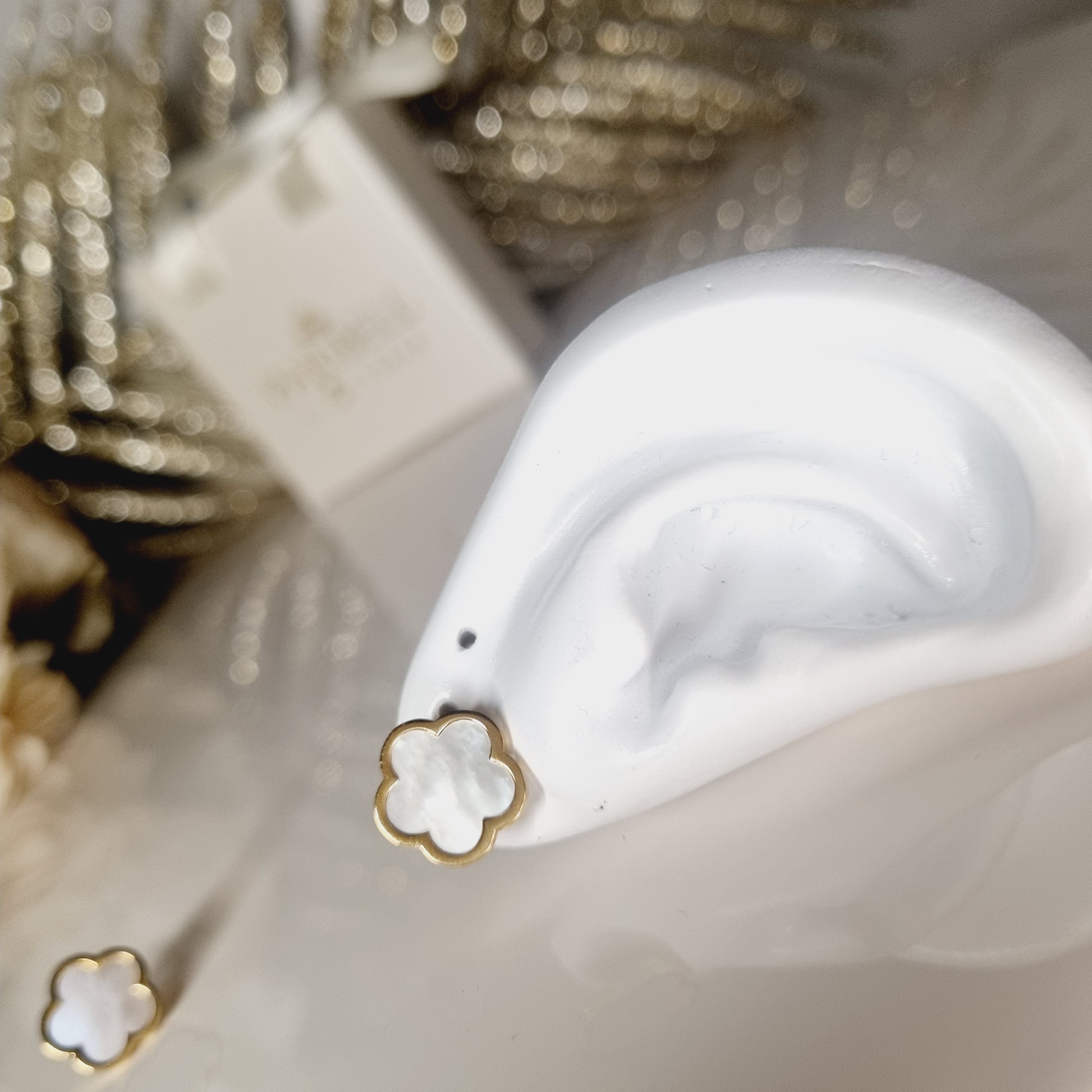 Photo de boucles d'oreilles dorées en acier inoxydable avec une pierre blanche nacrée en forme de trèfle à 5 feuilles. Un bijou élégant et symbolique, parfait pour un style raffiné.