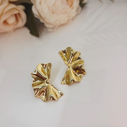 Boucles d’oreilles dorées effet drapé portées