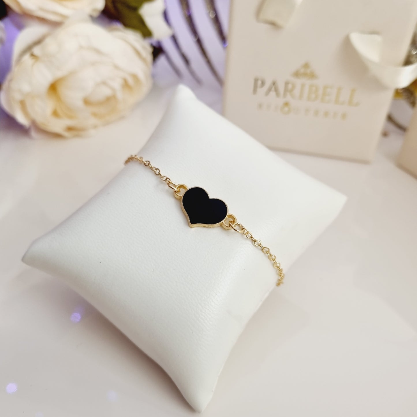 Bracelet doré ajustable avec cœur et pierre noire scintillante.