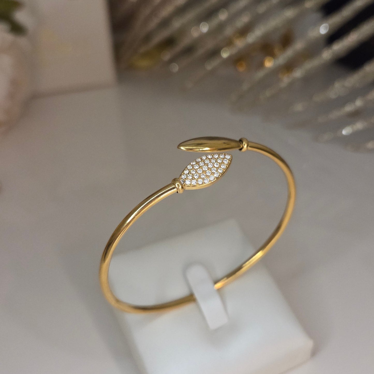 Bracelet doré en acier inoxydable. Jean très classe couleur or avec des feuilles aux extrémités dont une ornée de strass.