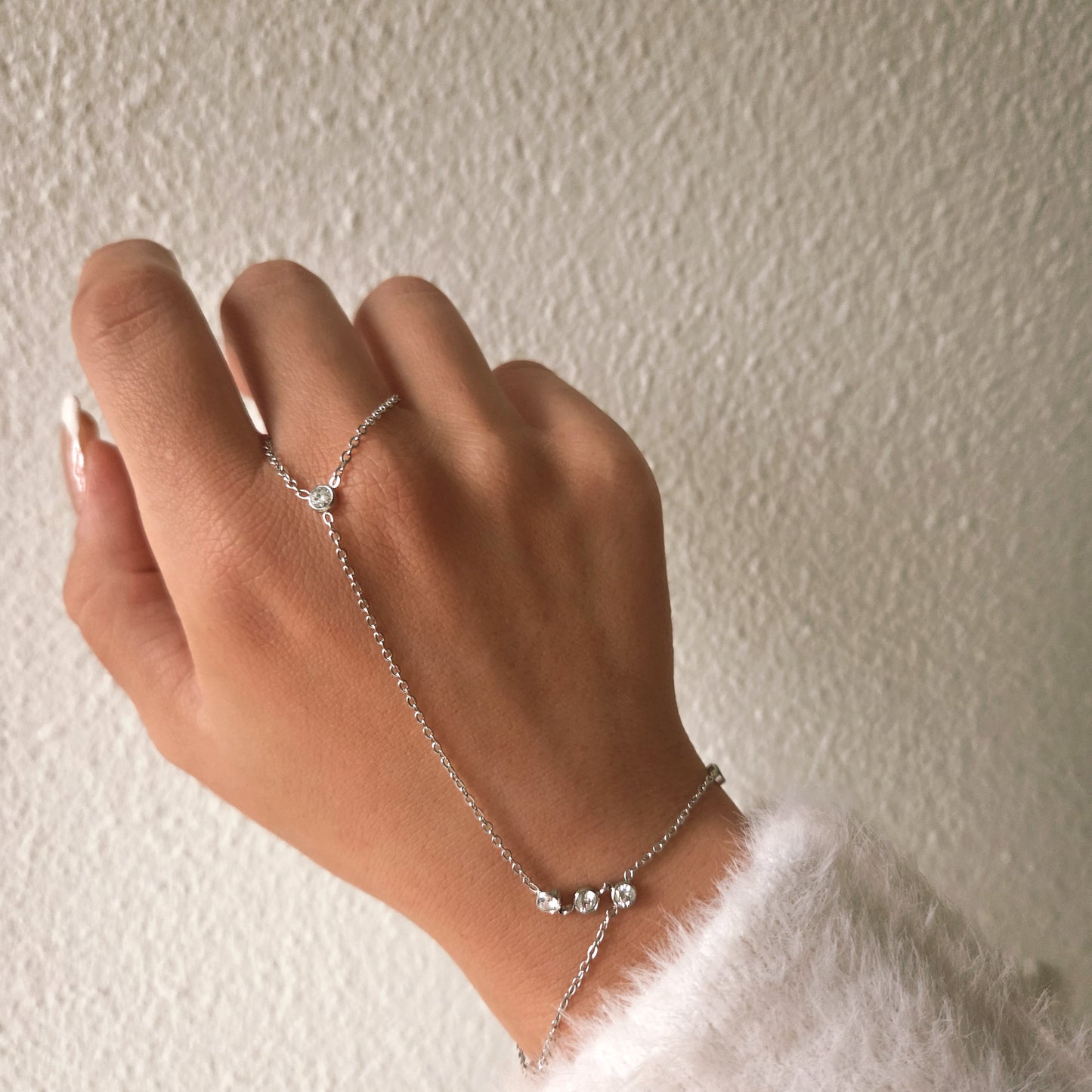 Bracelet main chaîne argenté avec cristaux brillants reliant poignet et doigt, bijou élégant et féminin