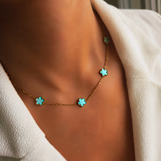 Collier doré avec motifs trèfles turquoise porté au cou, bijou élégant et lumineux