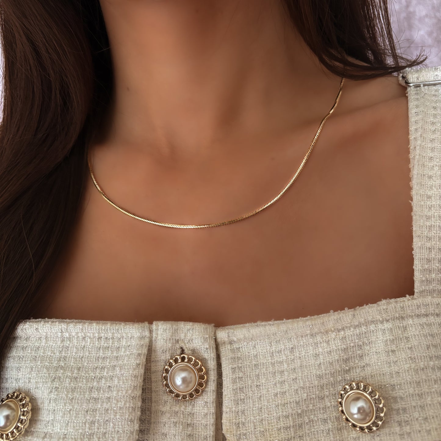 Collier serpent en acier inoxydable, chaîne plate fine et brillante portée autour du cou. Bijou minimaliste, résistant à l’eau et idéal pour un style élégant.