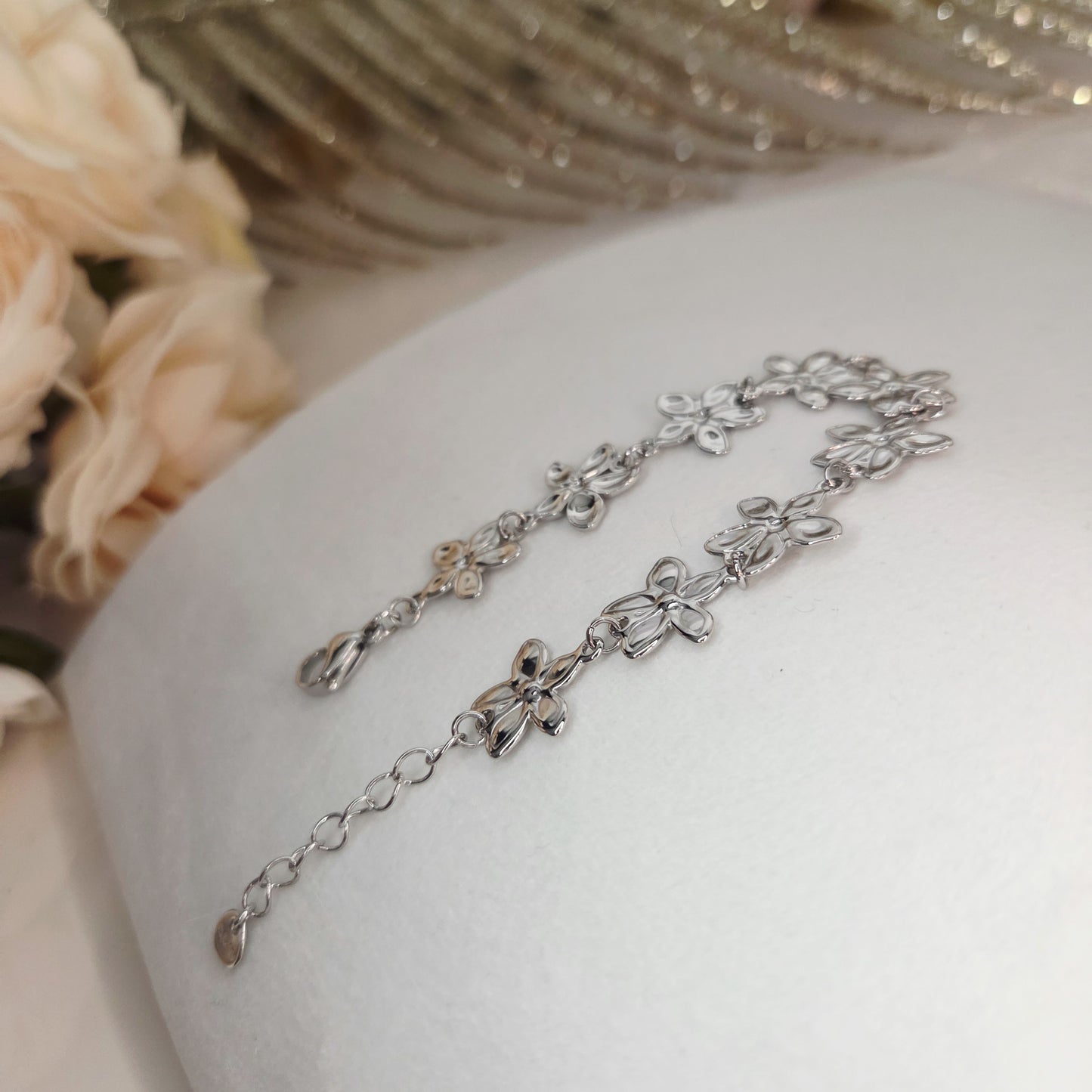Bracelet fleurs ajourées présenté à plat, montrant l’alignement harmonieux des motifs et la chaîne d’ajustement.