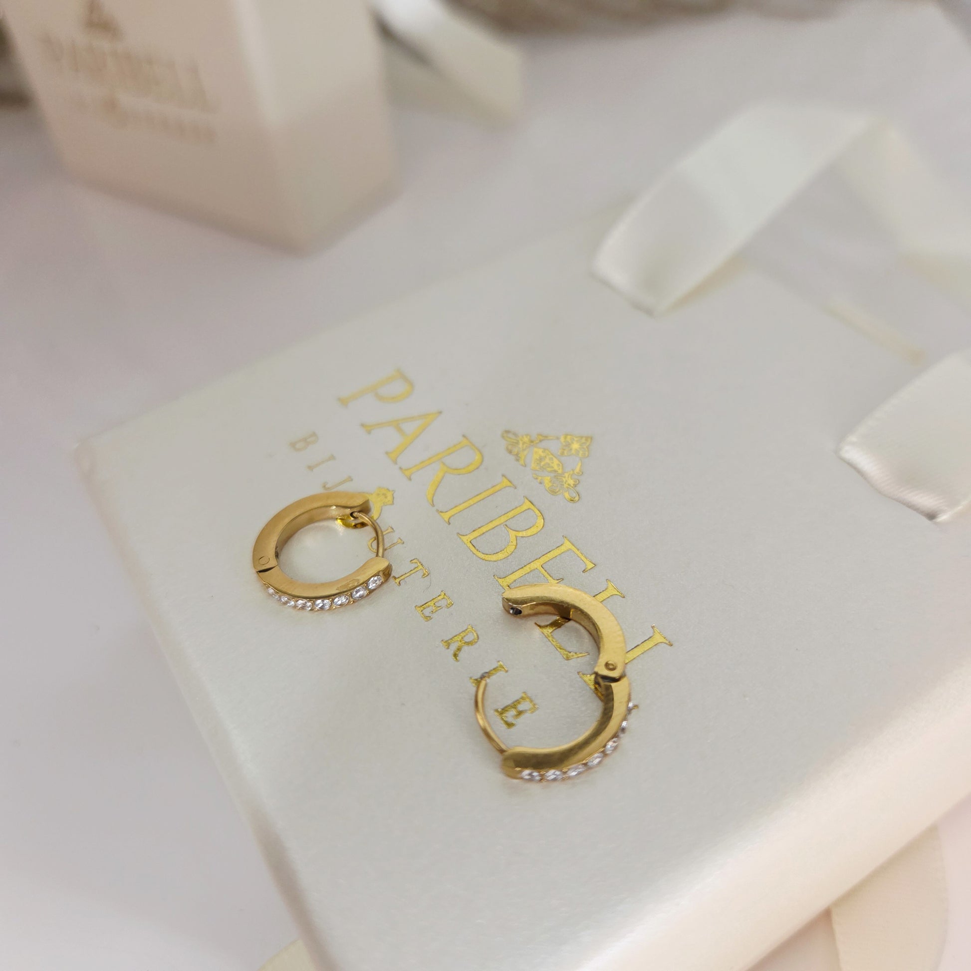 Paire de boucles d’oreilles créoles fines serties de cristaux portées à l’oreille, bijou élégant et minimaliste zoom sur les détails du fermoir