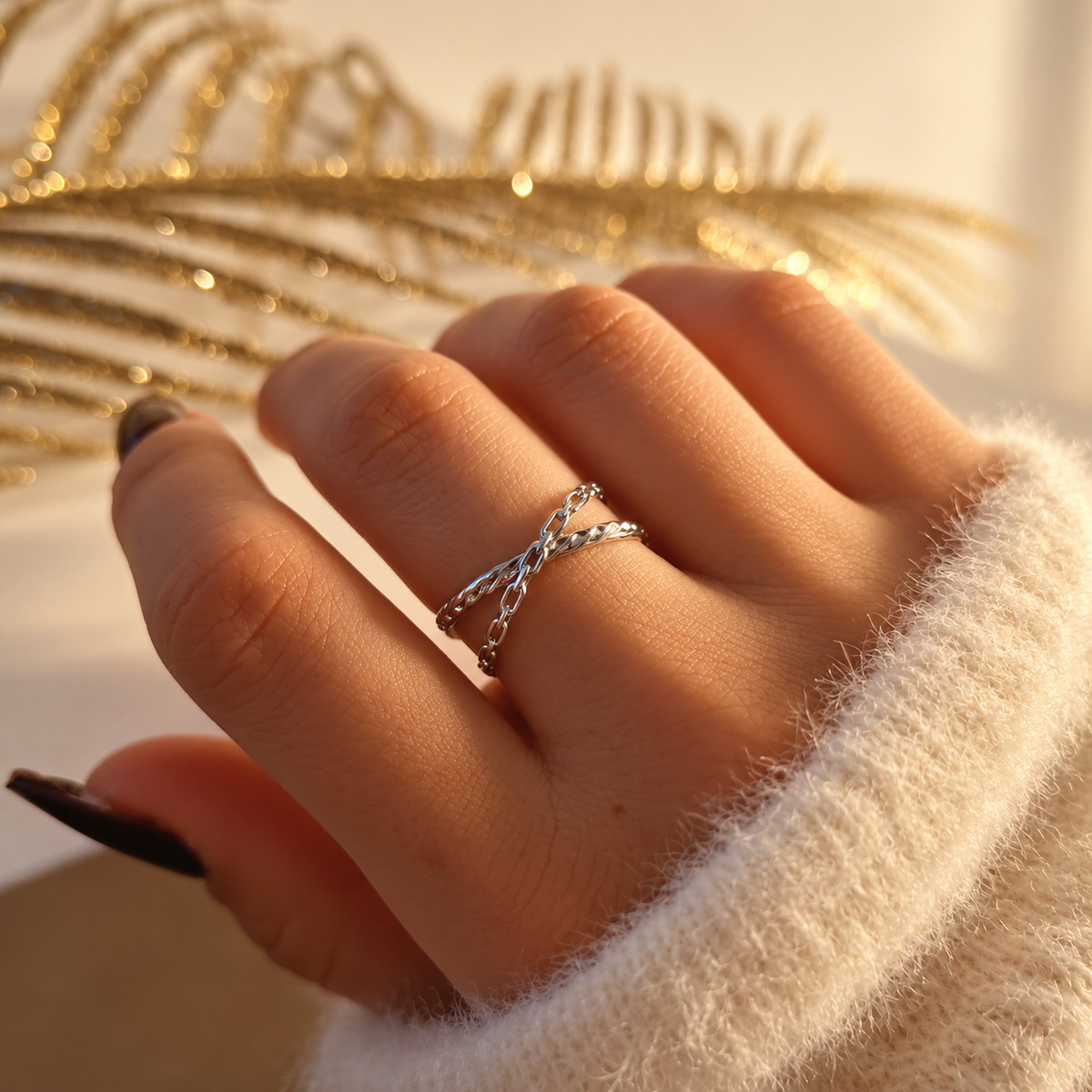 Bague argentée à deux chaînes de mailles différentes croisées sur le dessus de la main