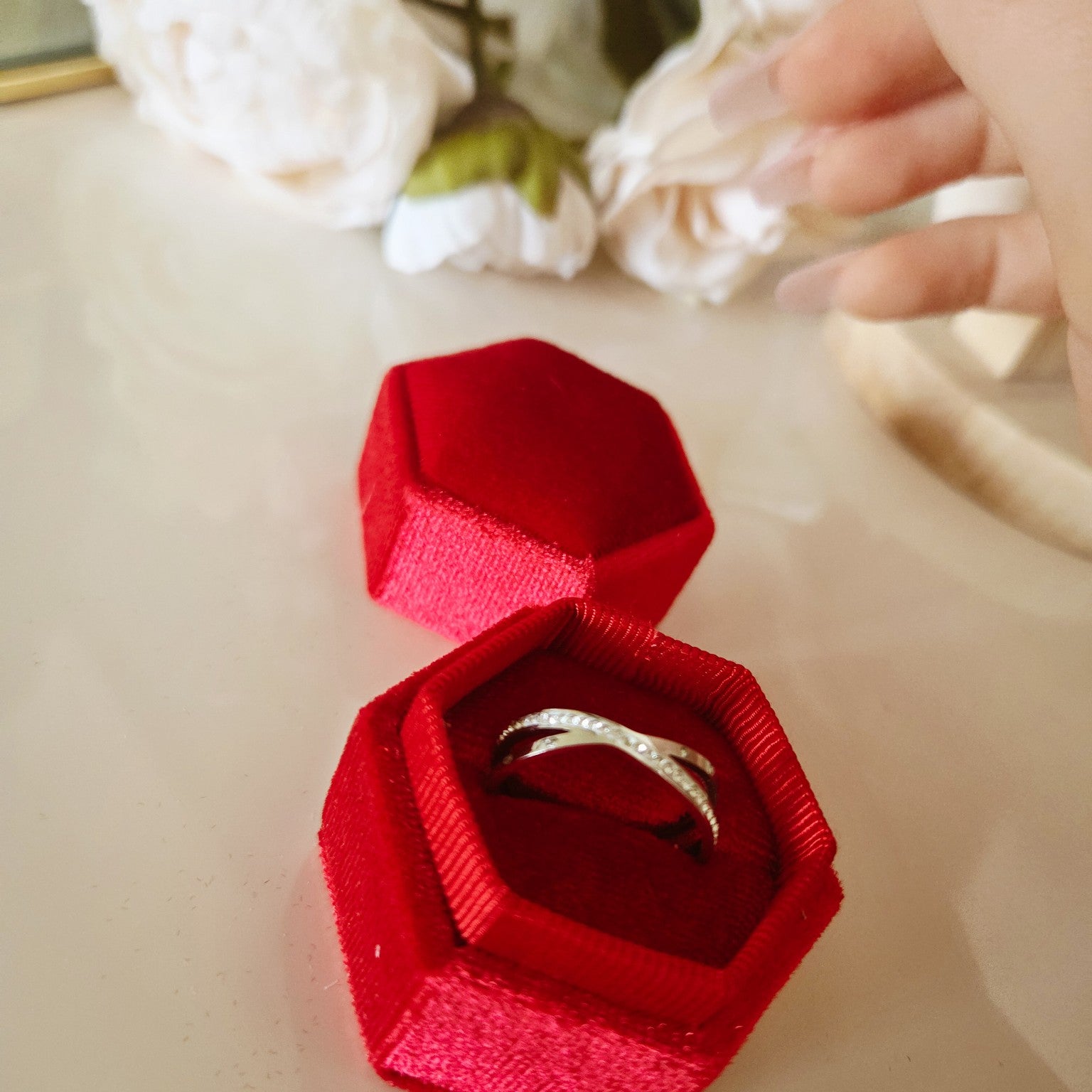 Bague croisée argentée pavée présentée dans un écrin rouge