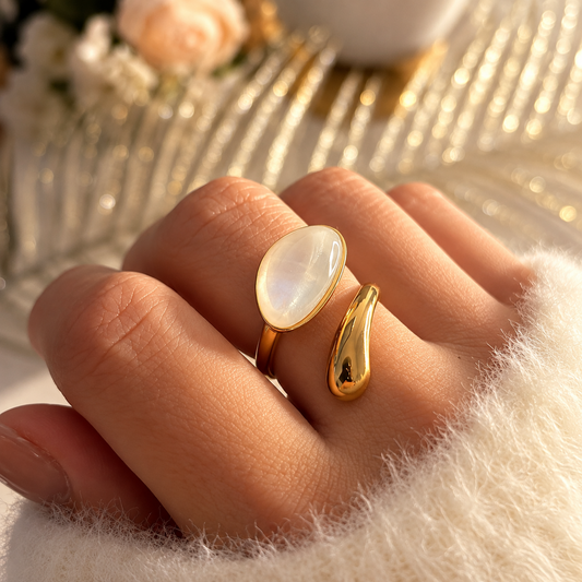 Bague dorée ouverte avec un grand motif ovale blanc aux reflets nacrés et un motif goutte doré
