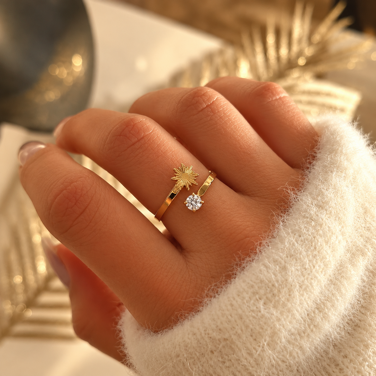 Bague dorée ouverte avec un motif soleil et une pierre ronde transparente, portée à la main