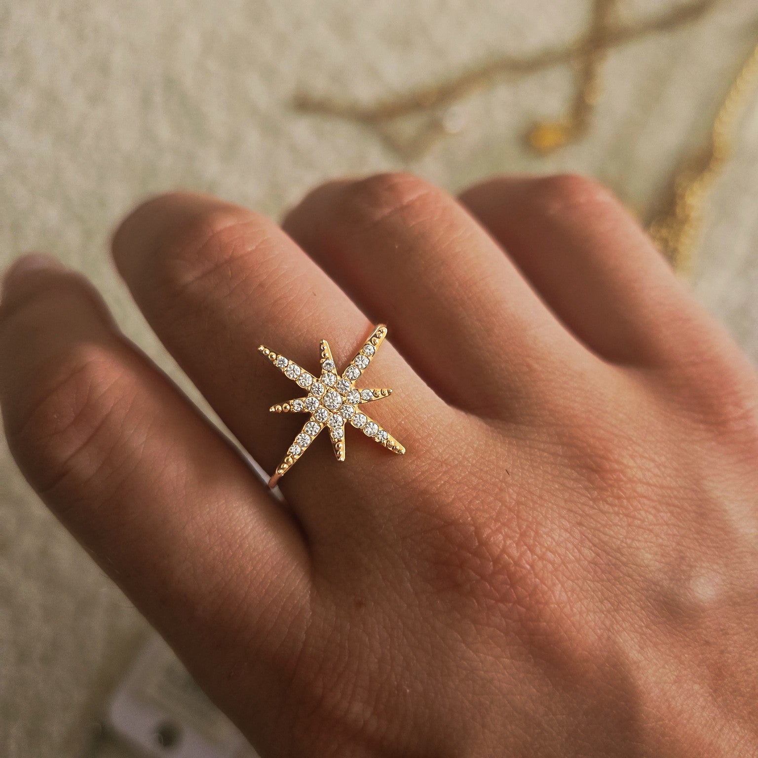 Bague dorée étoile pavée de strass portée à la main