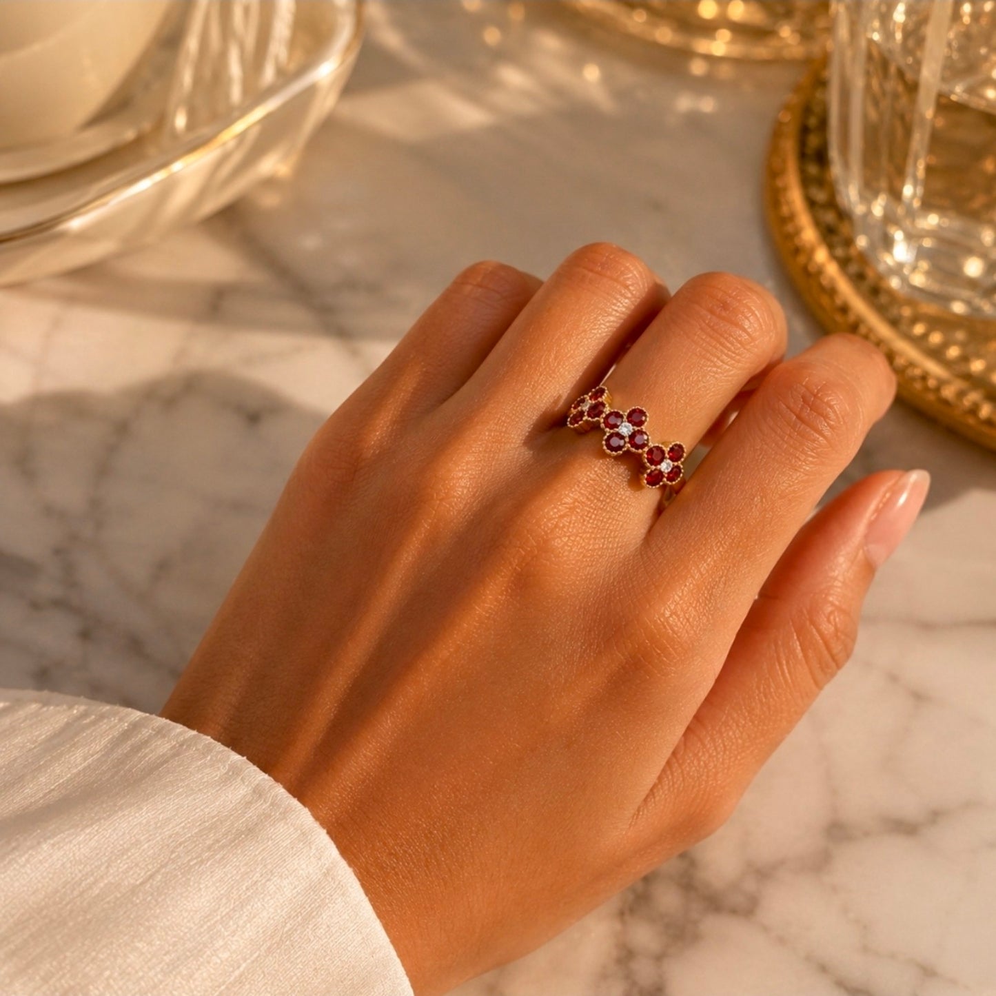 Bague dorée à fleurs rouges et blanches portée à la main
