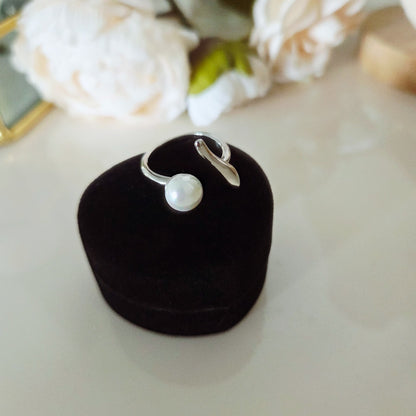Bague ouverte à perle blanche présentée sur un écrin noir