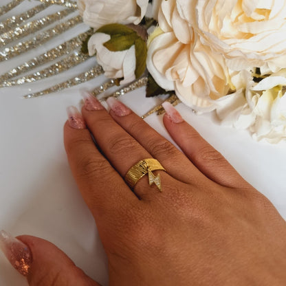 Bague dorée en acier inoxydable pour femme. Bague épaille, avec breloque vpendante en forme d'éclair orné de strass. Taille réglable, convient pour tous les doigts.