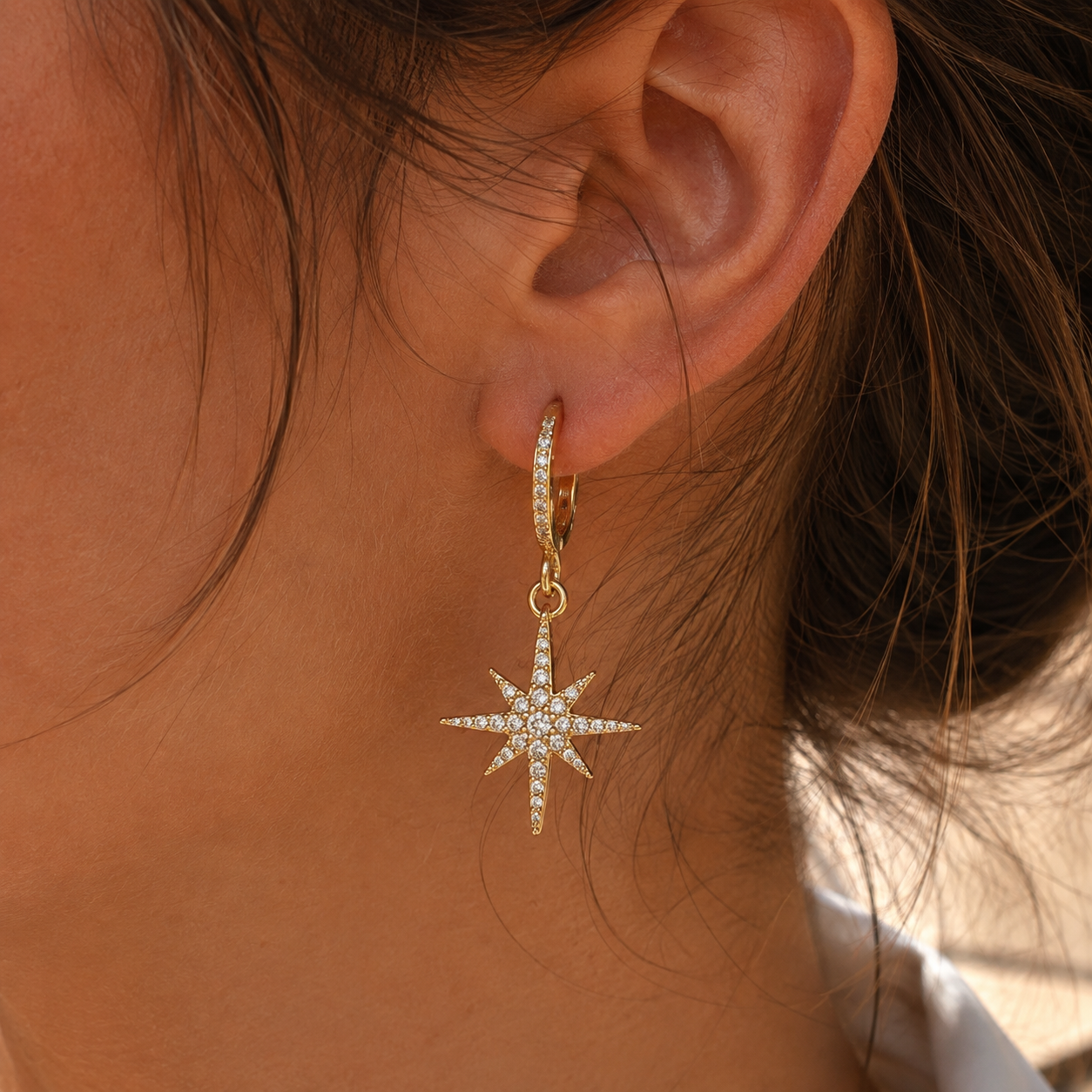 Boucles d’oreilles dorées avec pendentif étoile serti de pierres blanches
