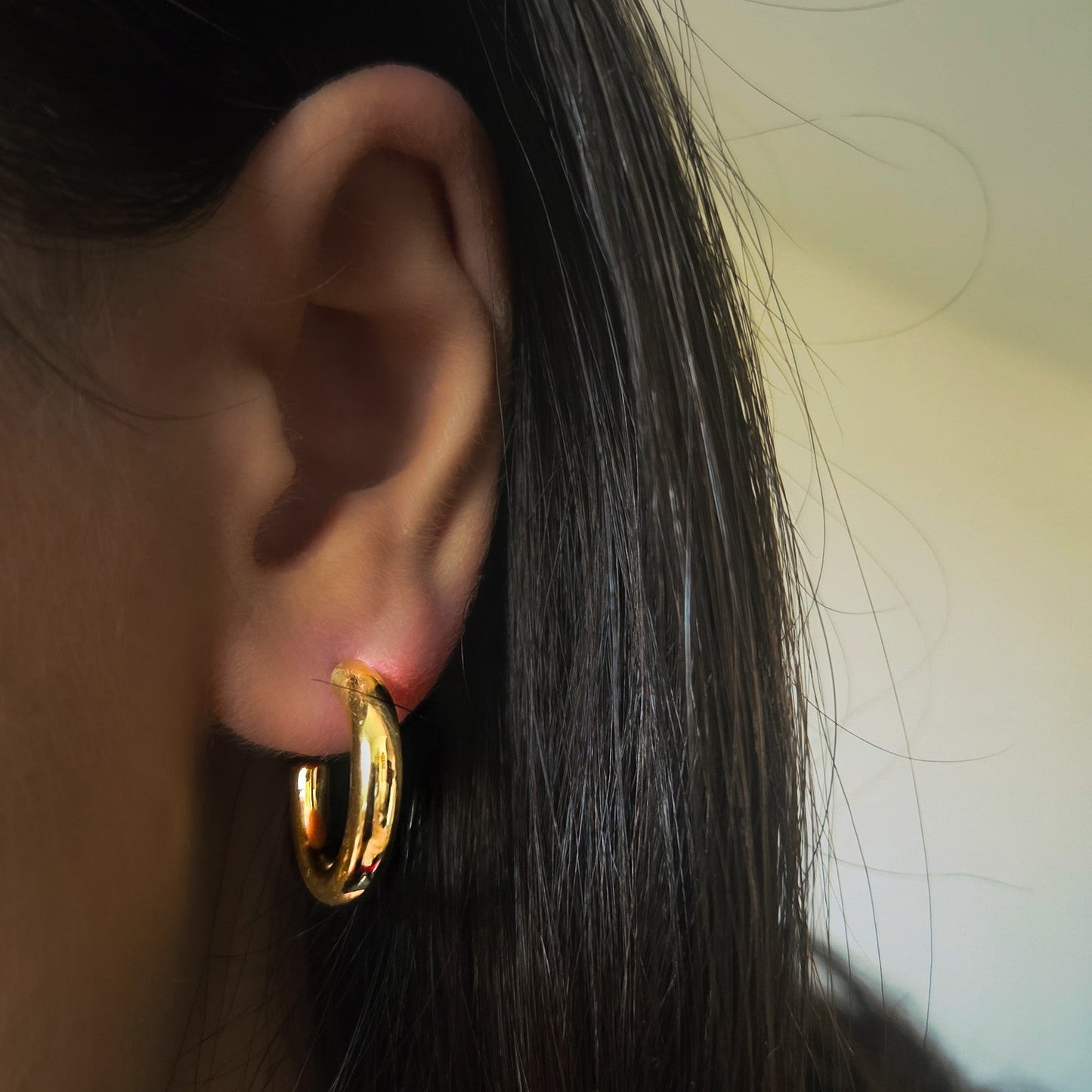 Boucles d’oreilles créoles dorées en acier inoxydable portées à l’oreille